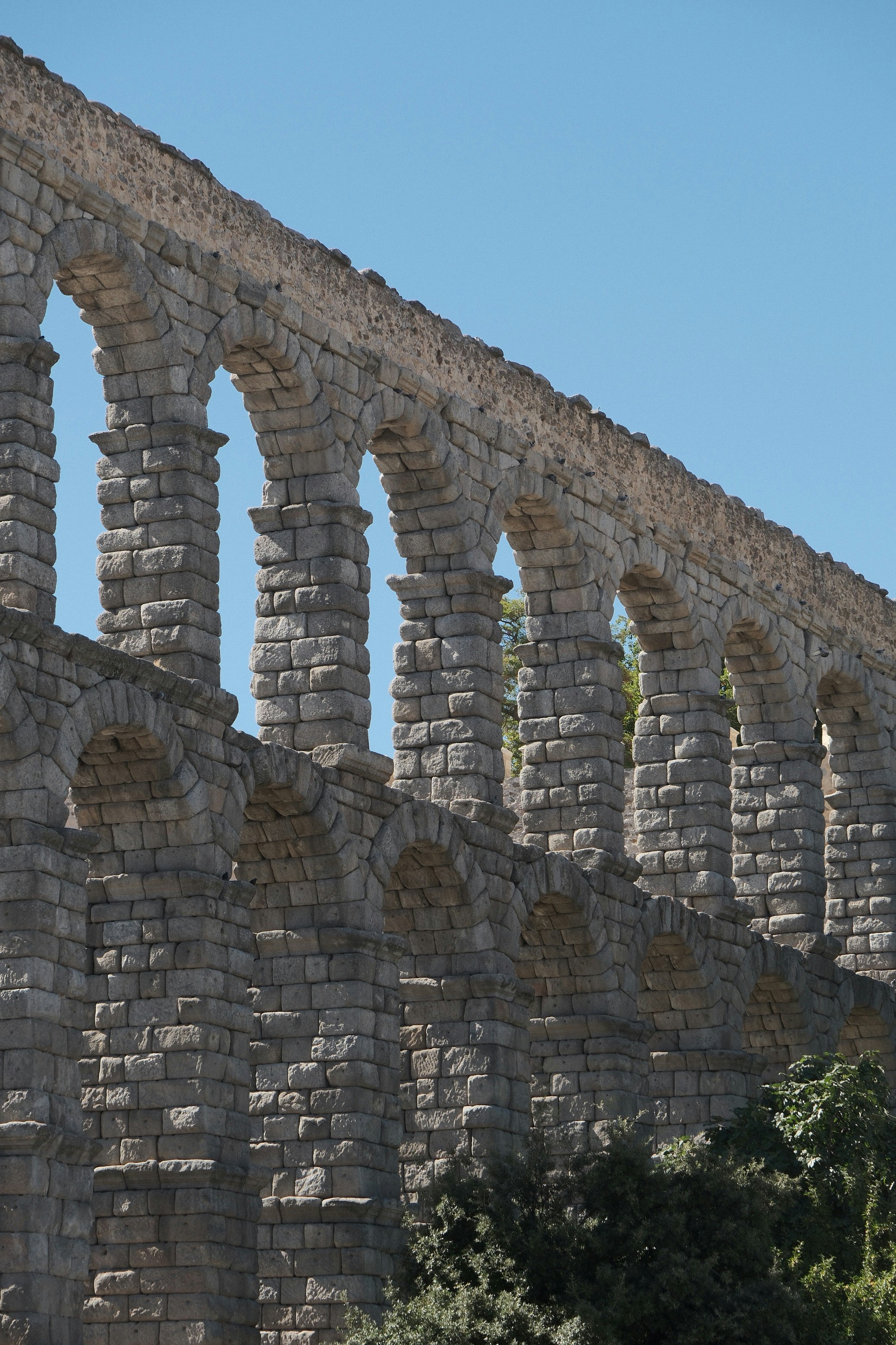 The ancient Roman aqueduct of Segovia with stone arches against a clear blue sky