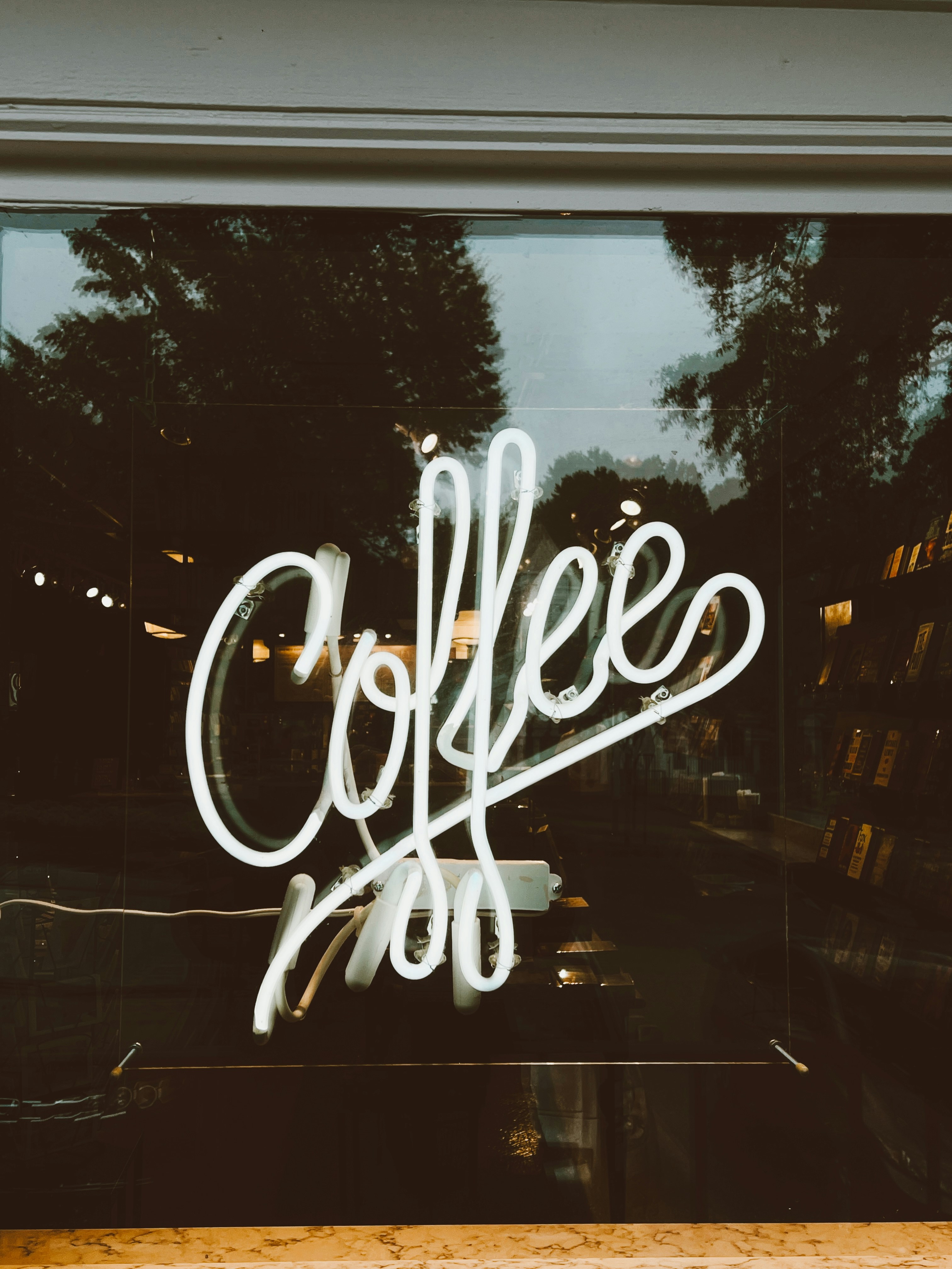 A white neon sign reading "coffee" in a shop window at night