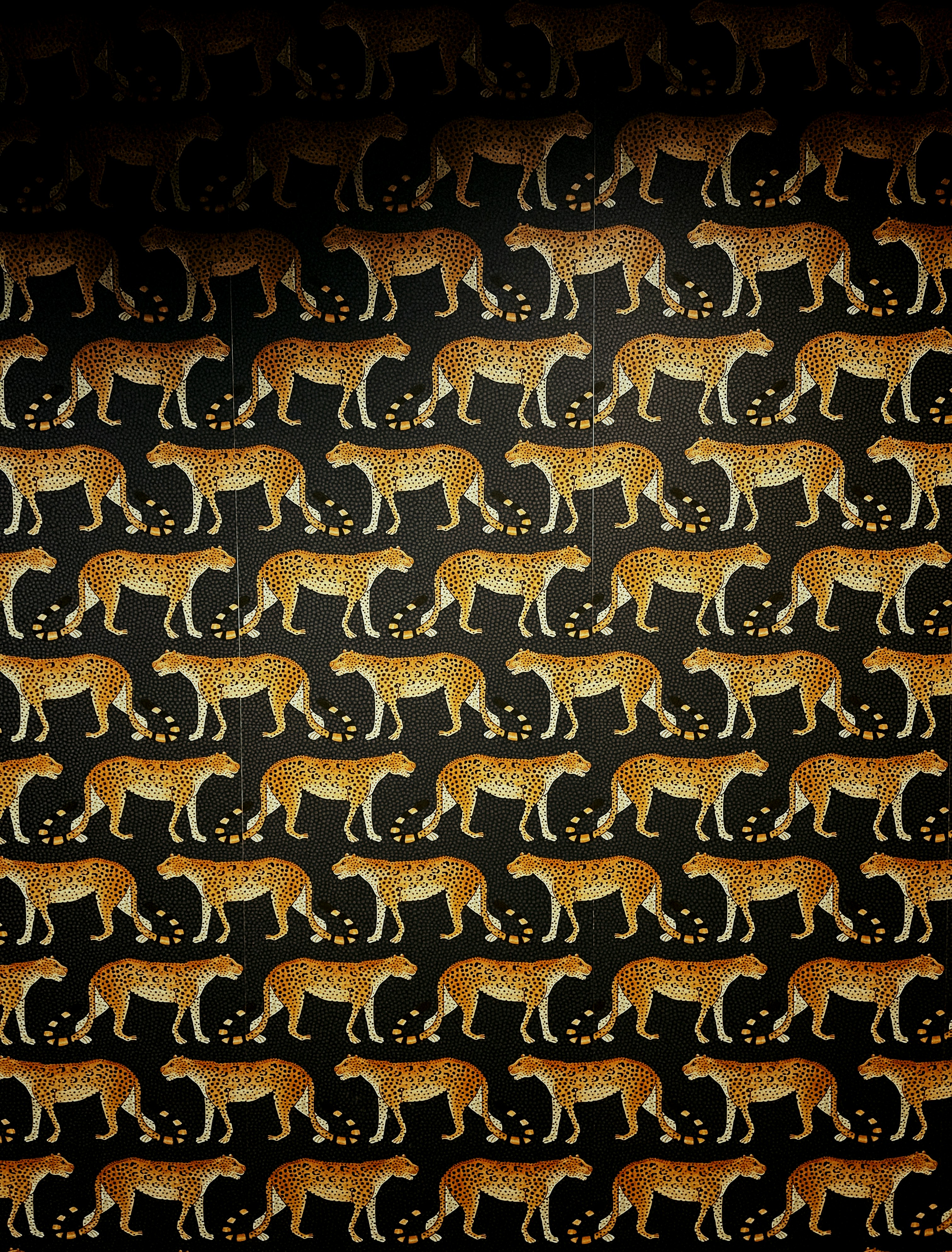 A repeating pattern of orange cheetahs with black spots on a dark background