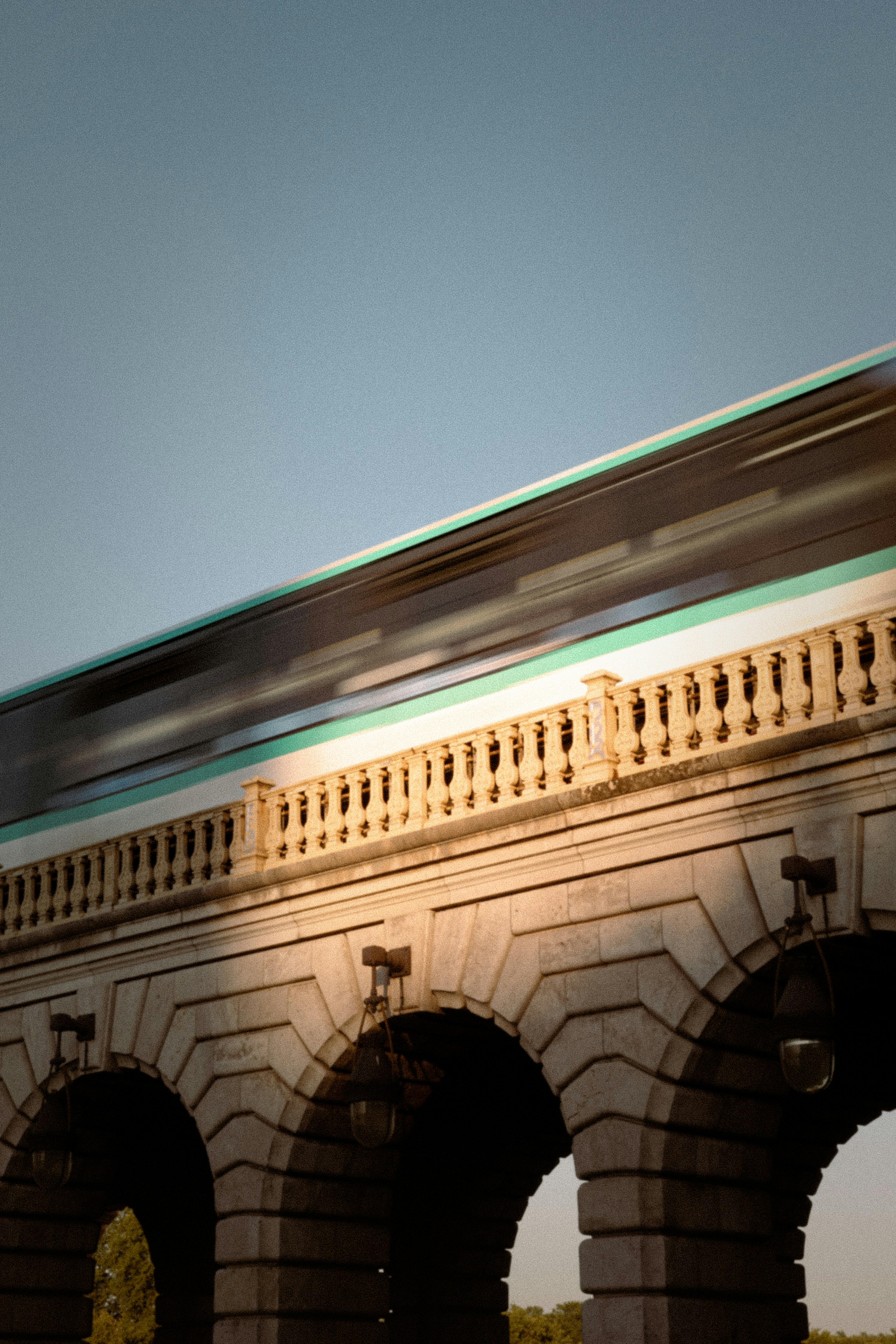 A blurred train moving across a stone arched bridge in Paris