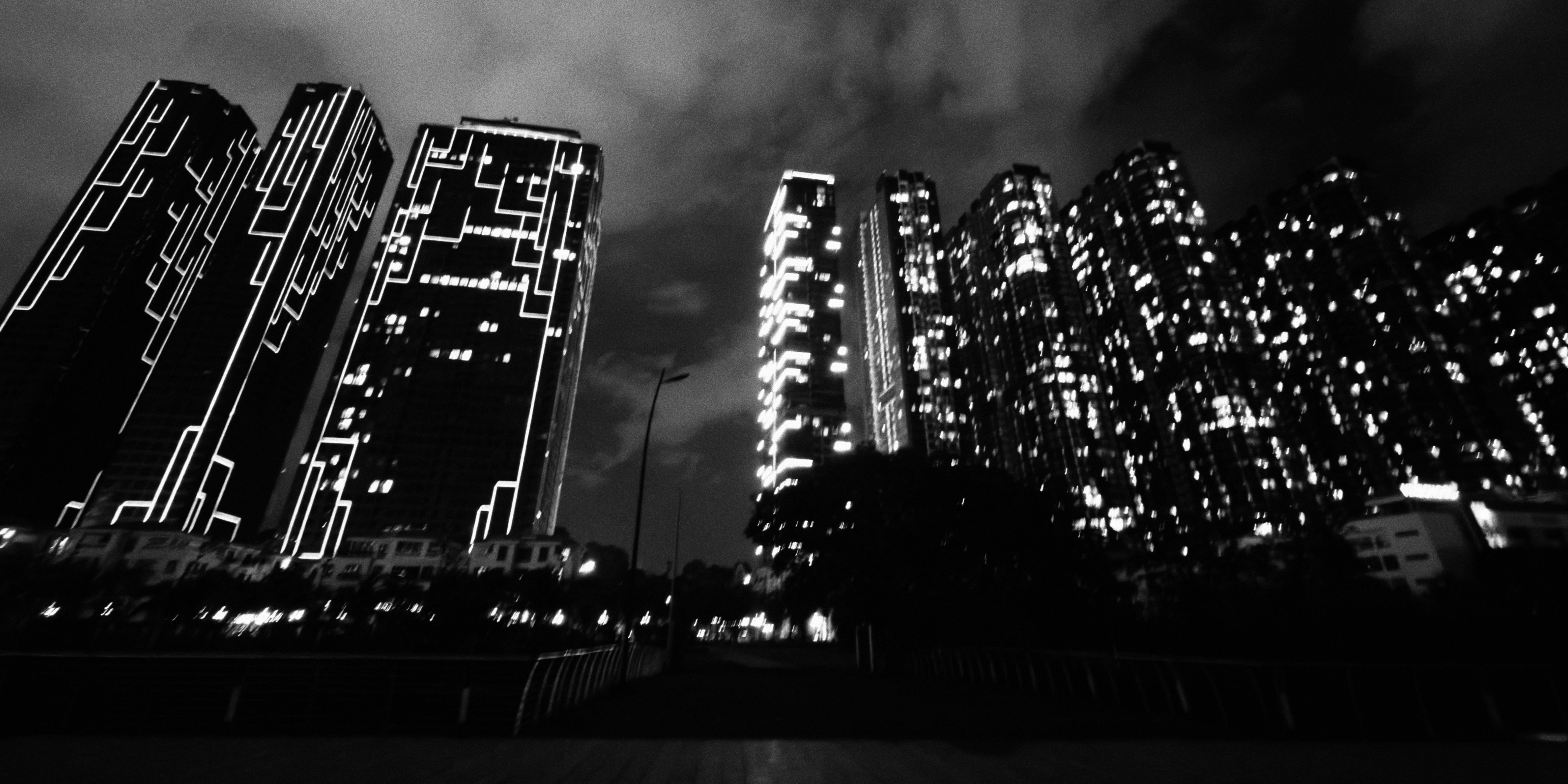 Black and white view of illuminated skyscrapers at night with glowing geometric patterns
