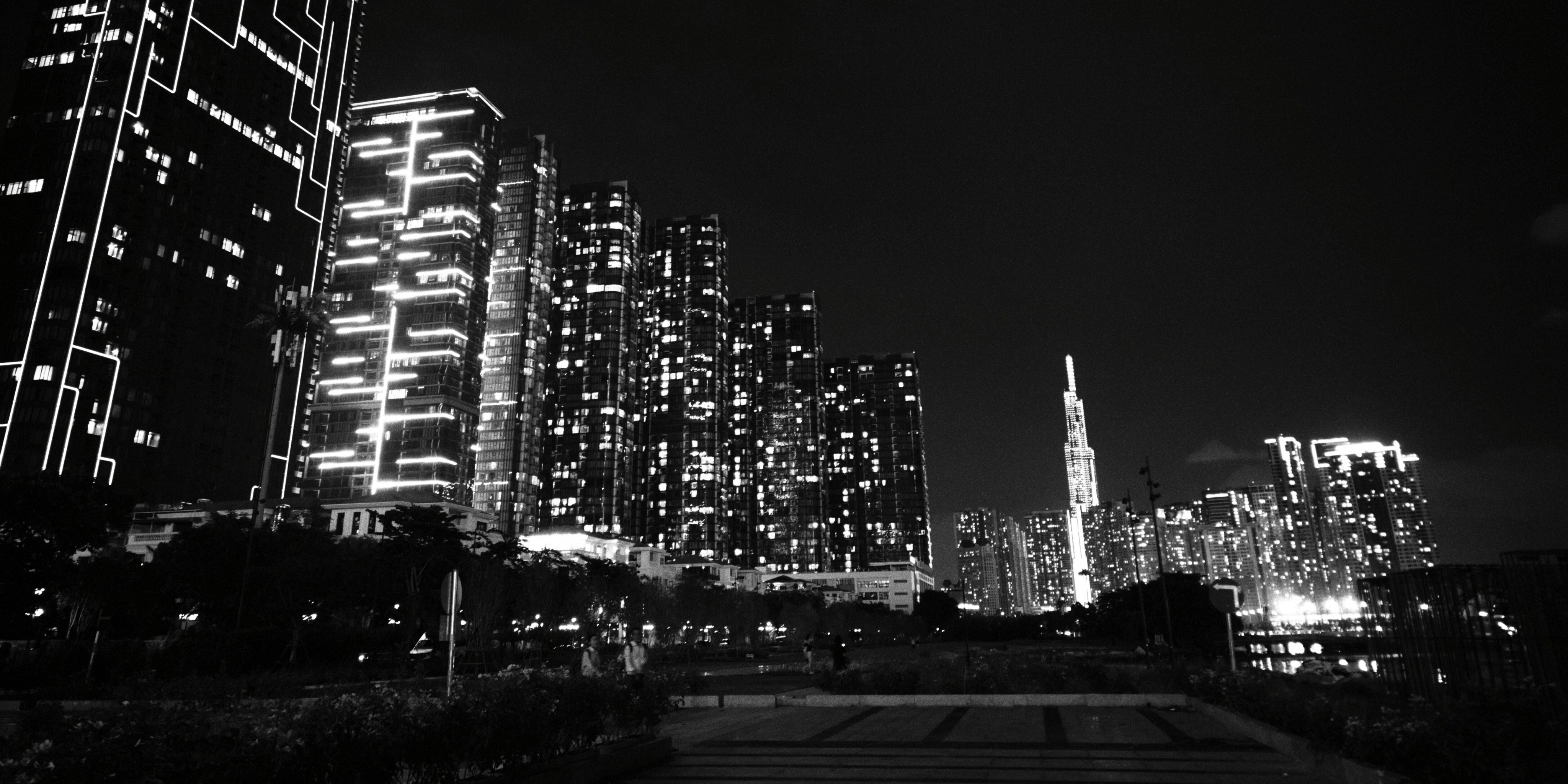 Black and white view of illuminated skyscrapers and a tall tower at night