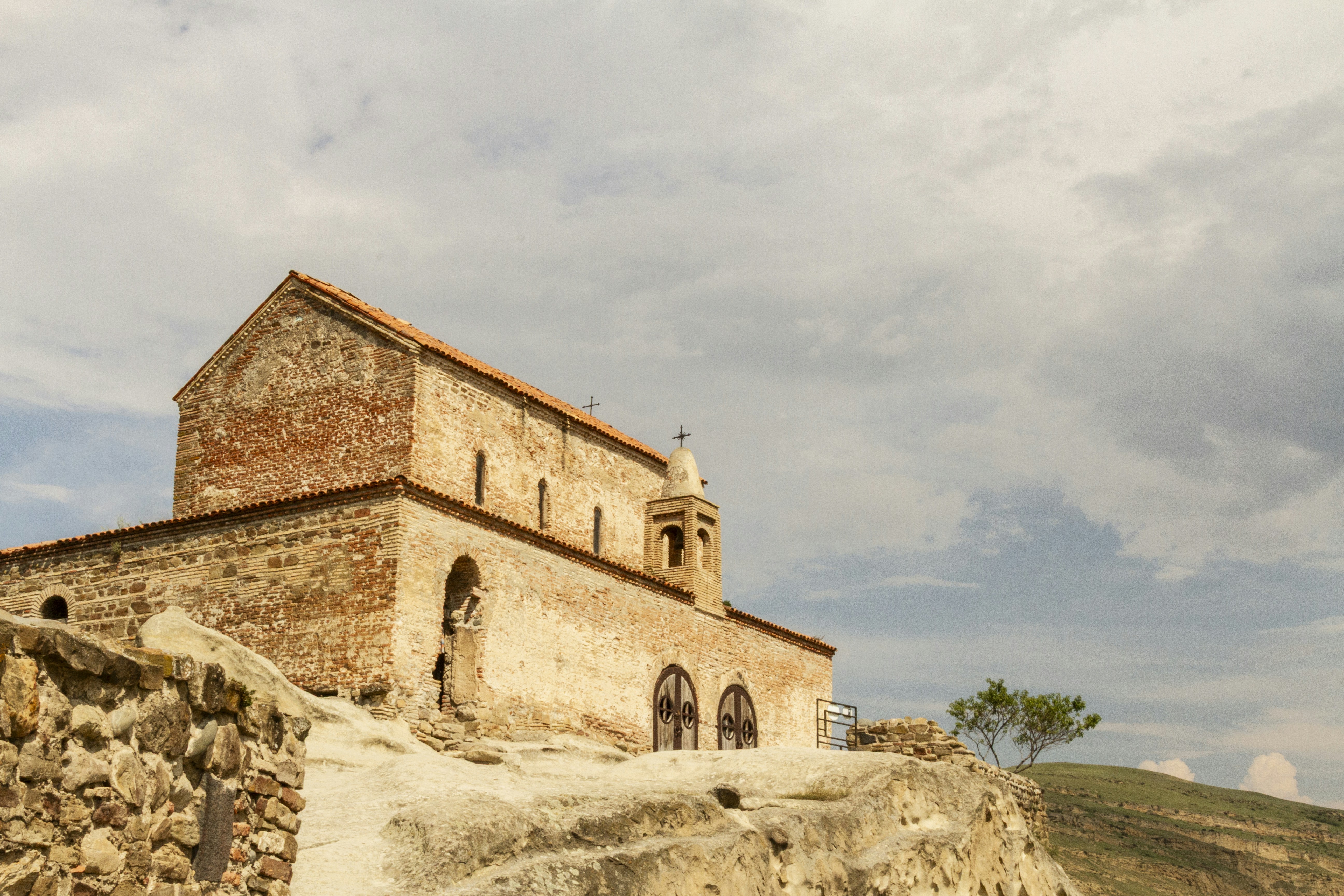 An ancient brick church with a small bell tower on a rocky hill