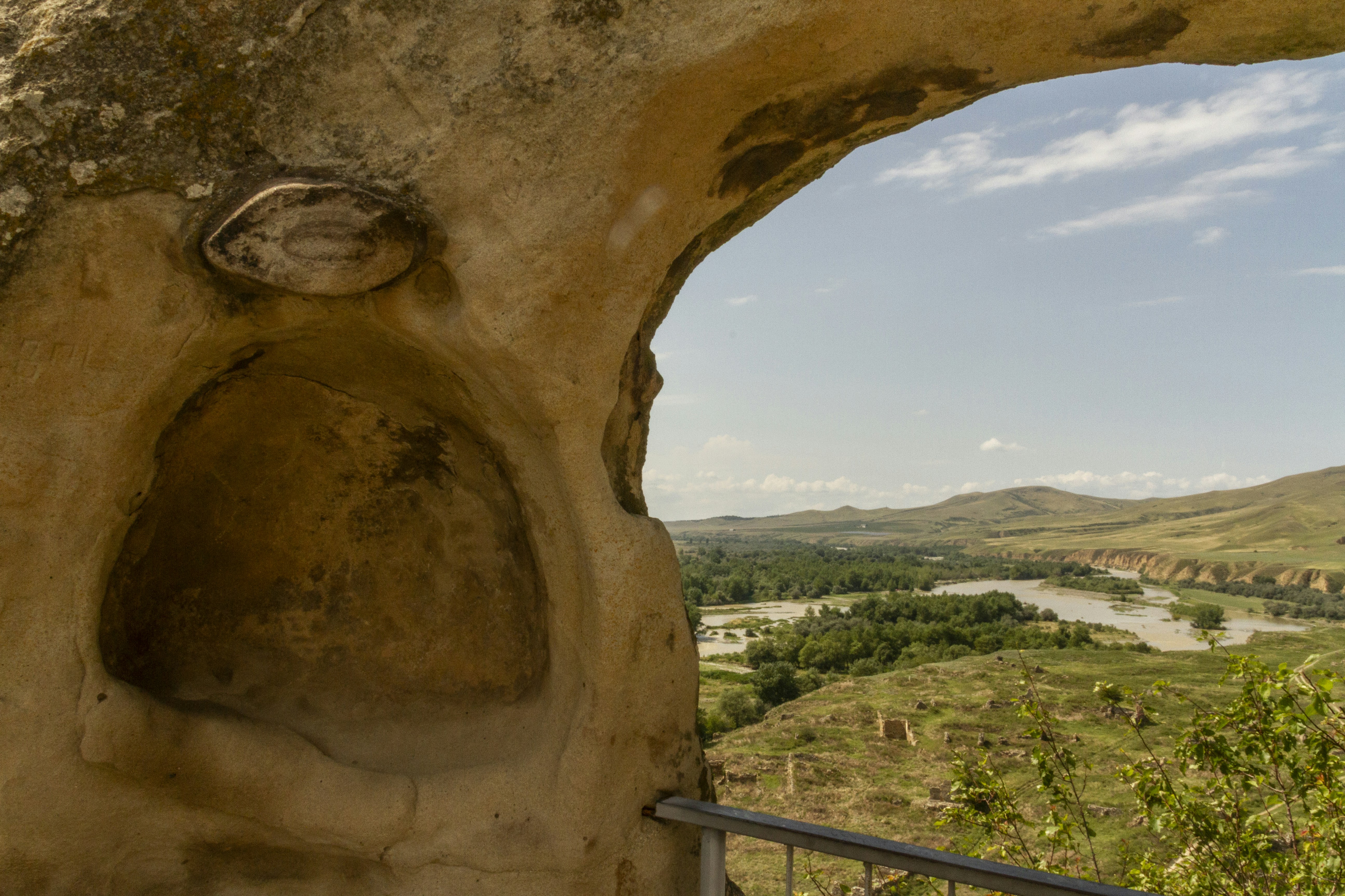 A view of a winding river through a carved stone archway in Uplistsikhe