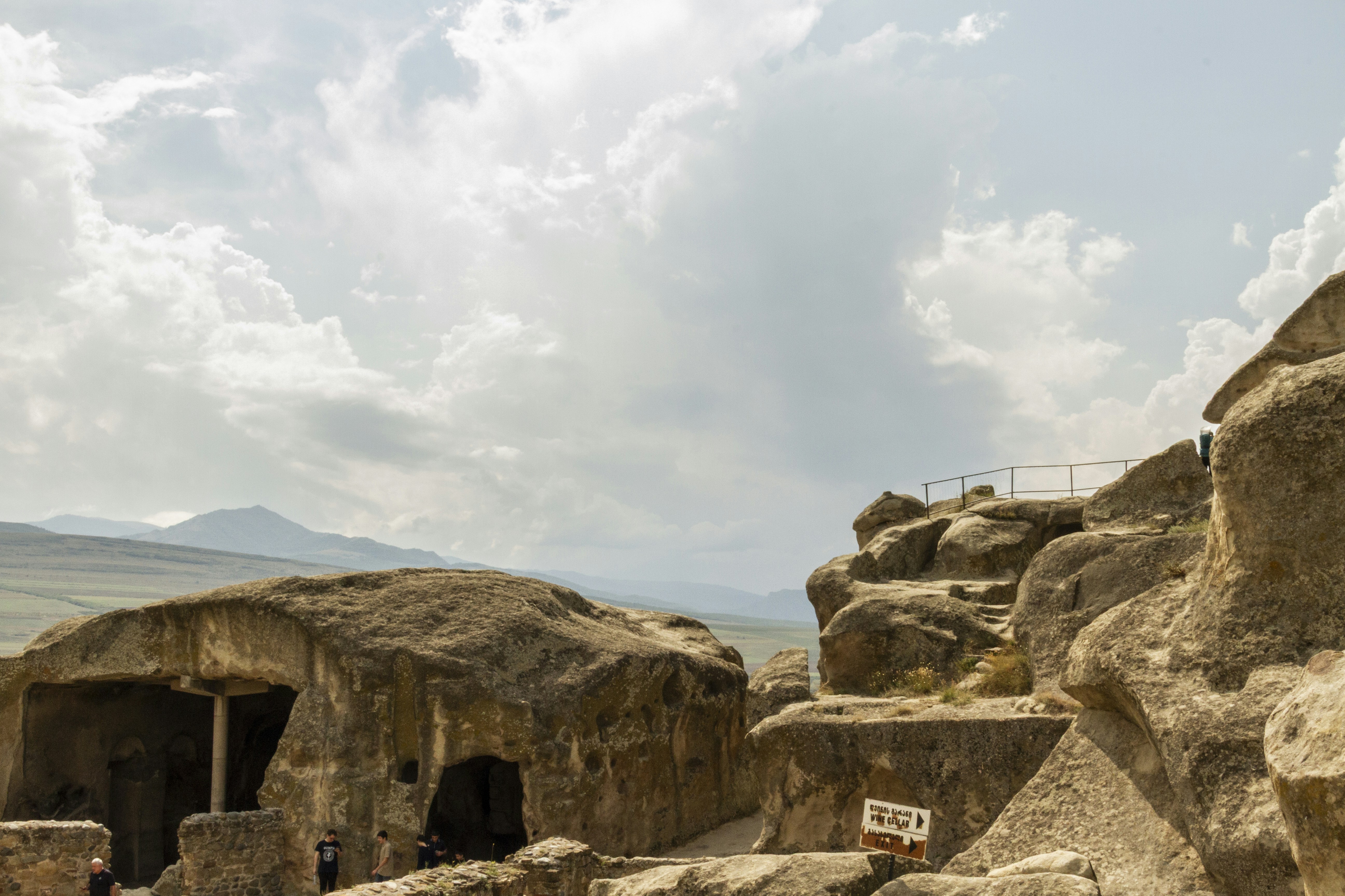 Ancient cave dwellings carved into sandstone rock formations under a cloudy sky
