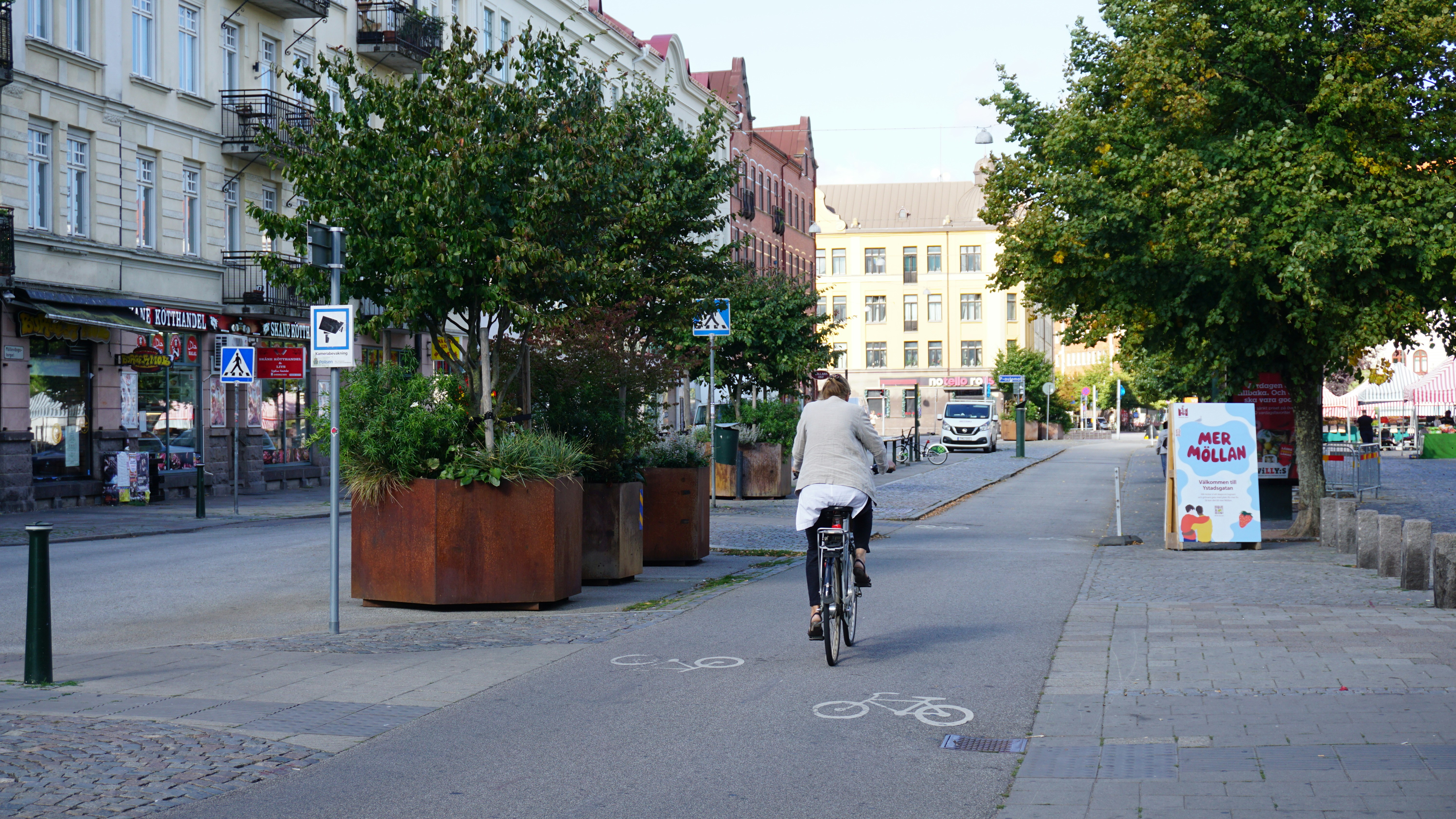 Person cycling on a city street past planters