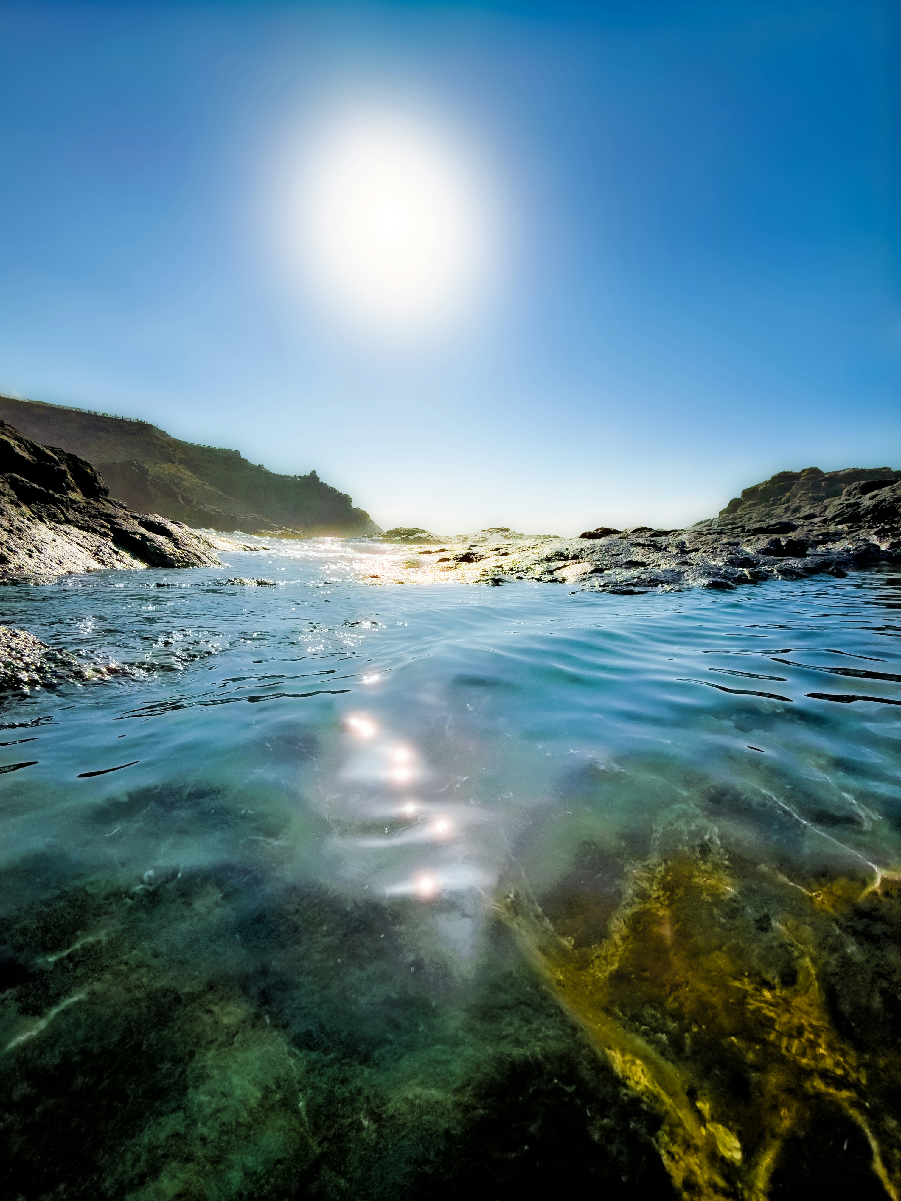 Eau claire dans une mare à marée rocheuse sous un soleil éclatant dans un ciel bleu