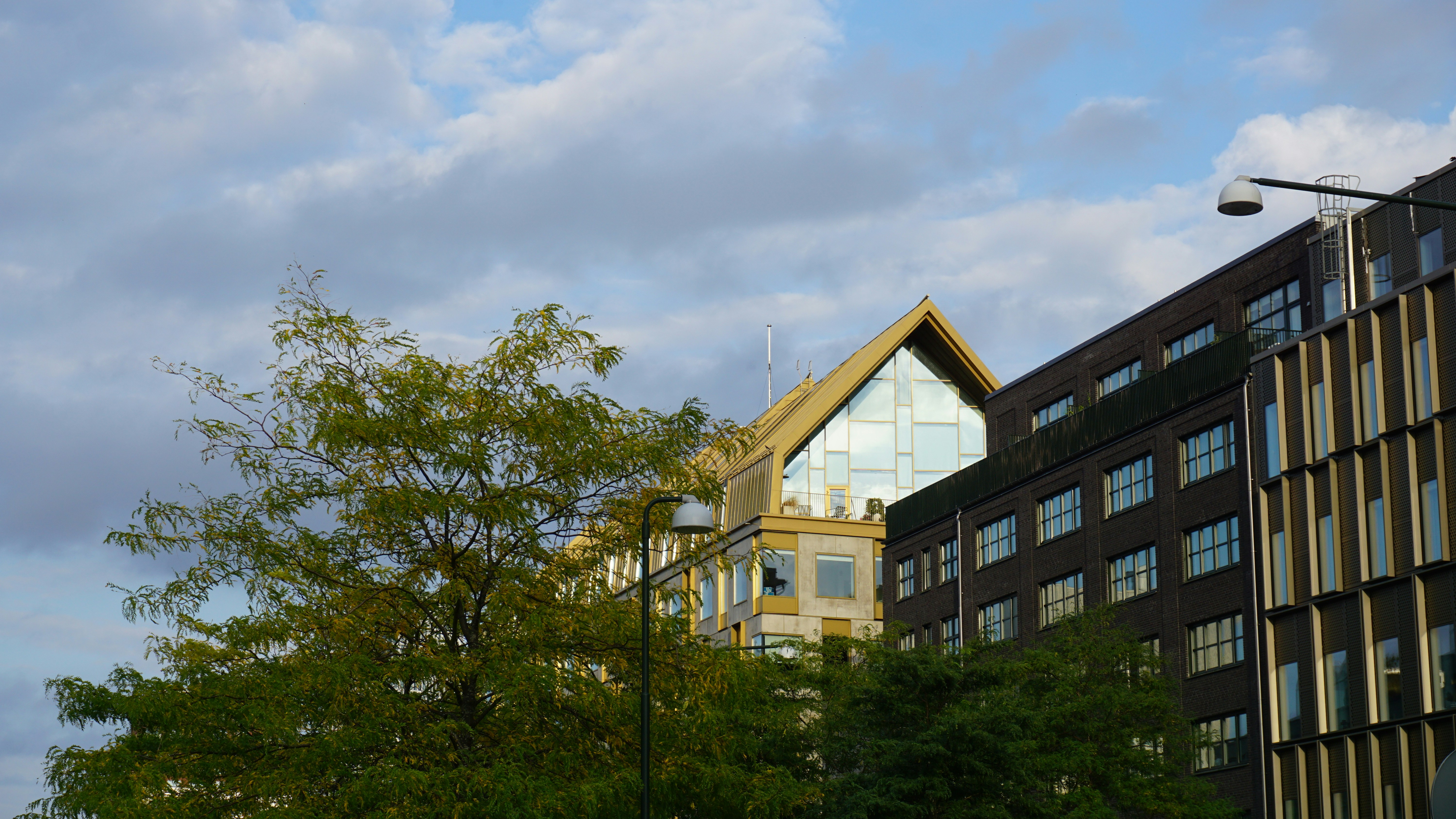 Modern buildings with glass facades and a gabled roof under a cloudy sky