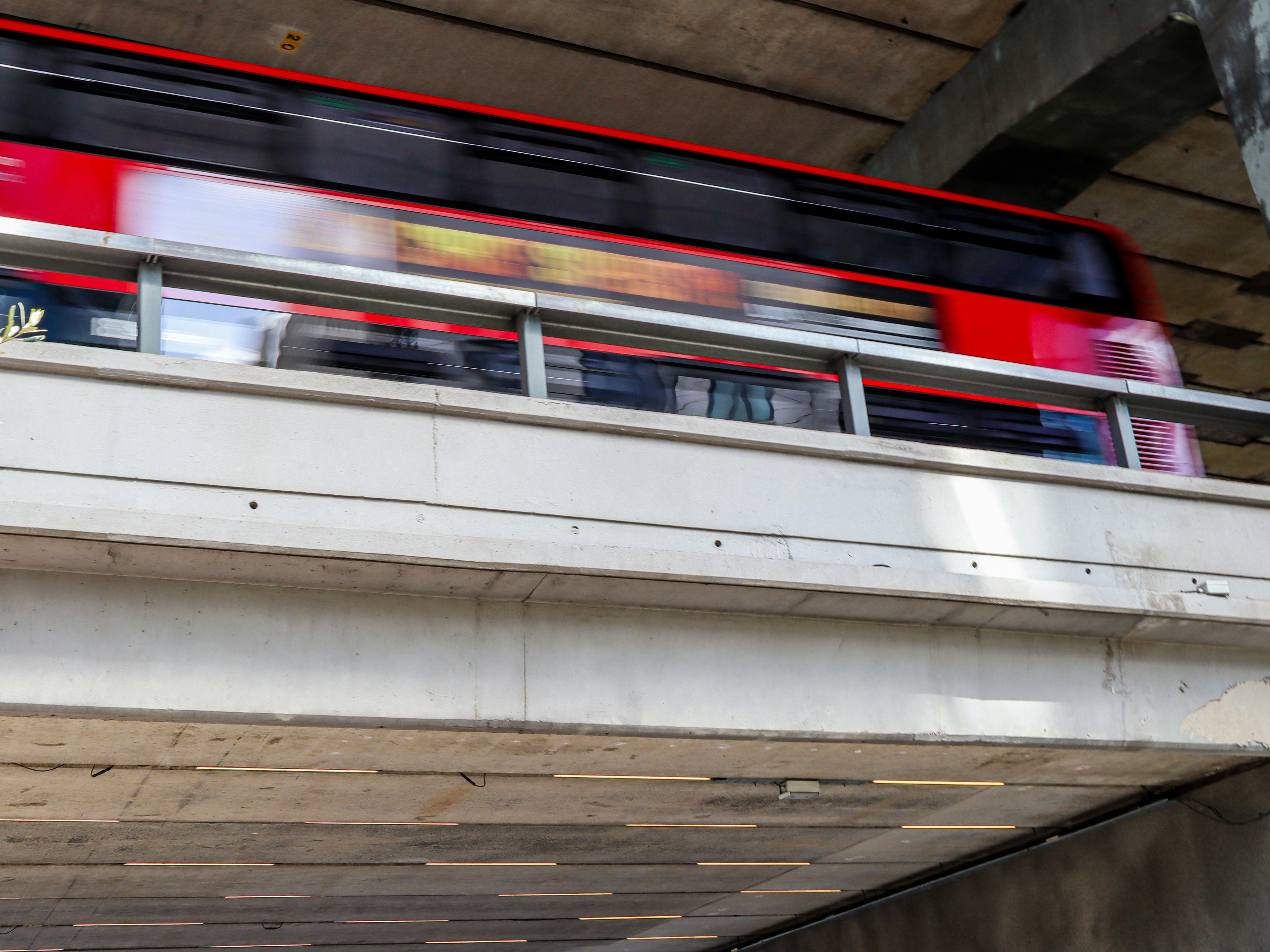Ein roter Doppeldeckerbus, der mit Bewegungsunschärfe über eine Betonbrücke fährt