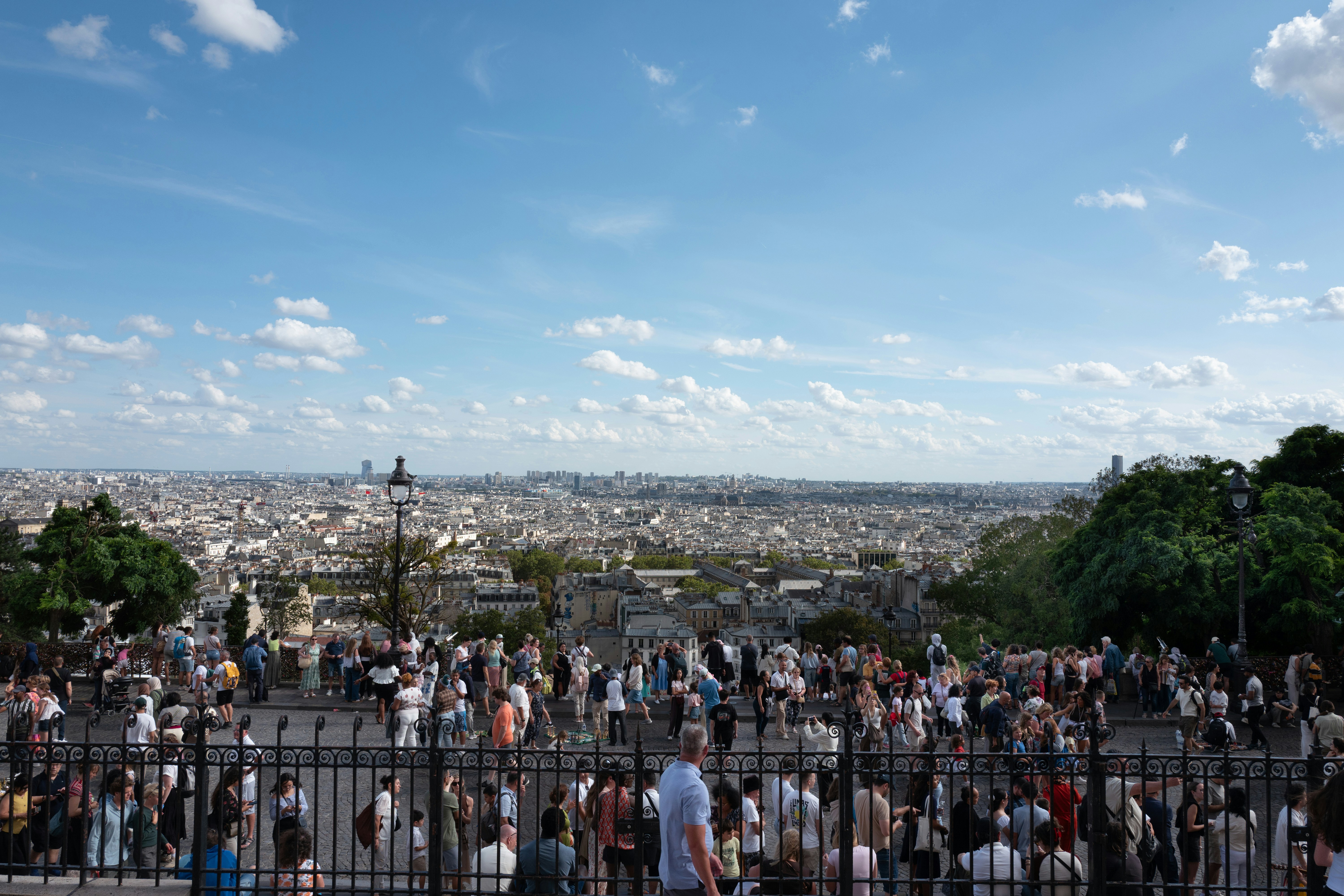 A crowd of people on a terrace overlooking the sprawling city of Paris