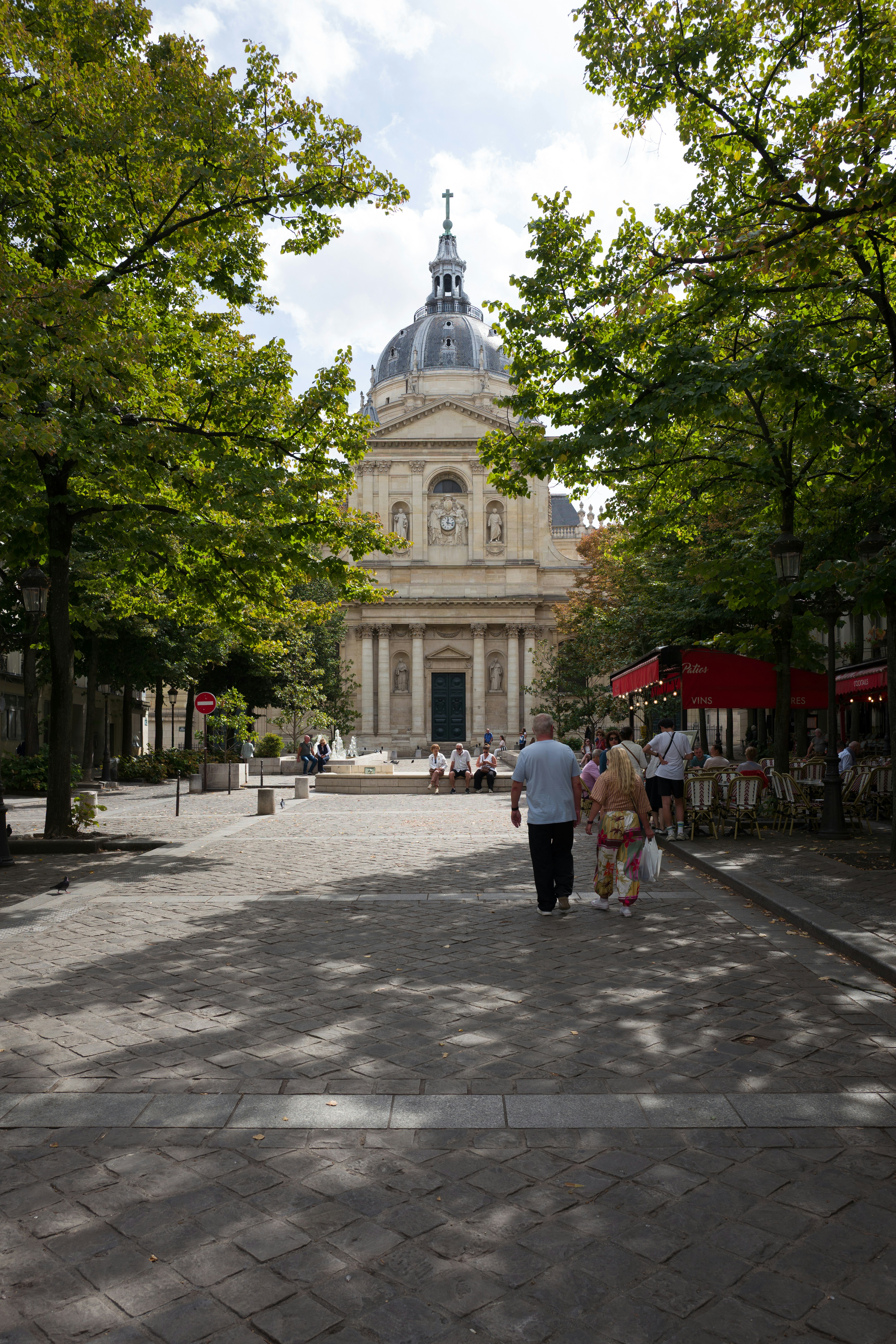People walking on a cobblestone square toward the Institut de France in Paris