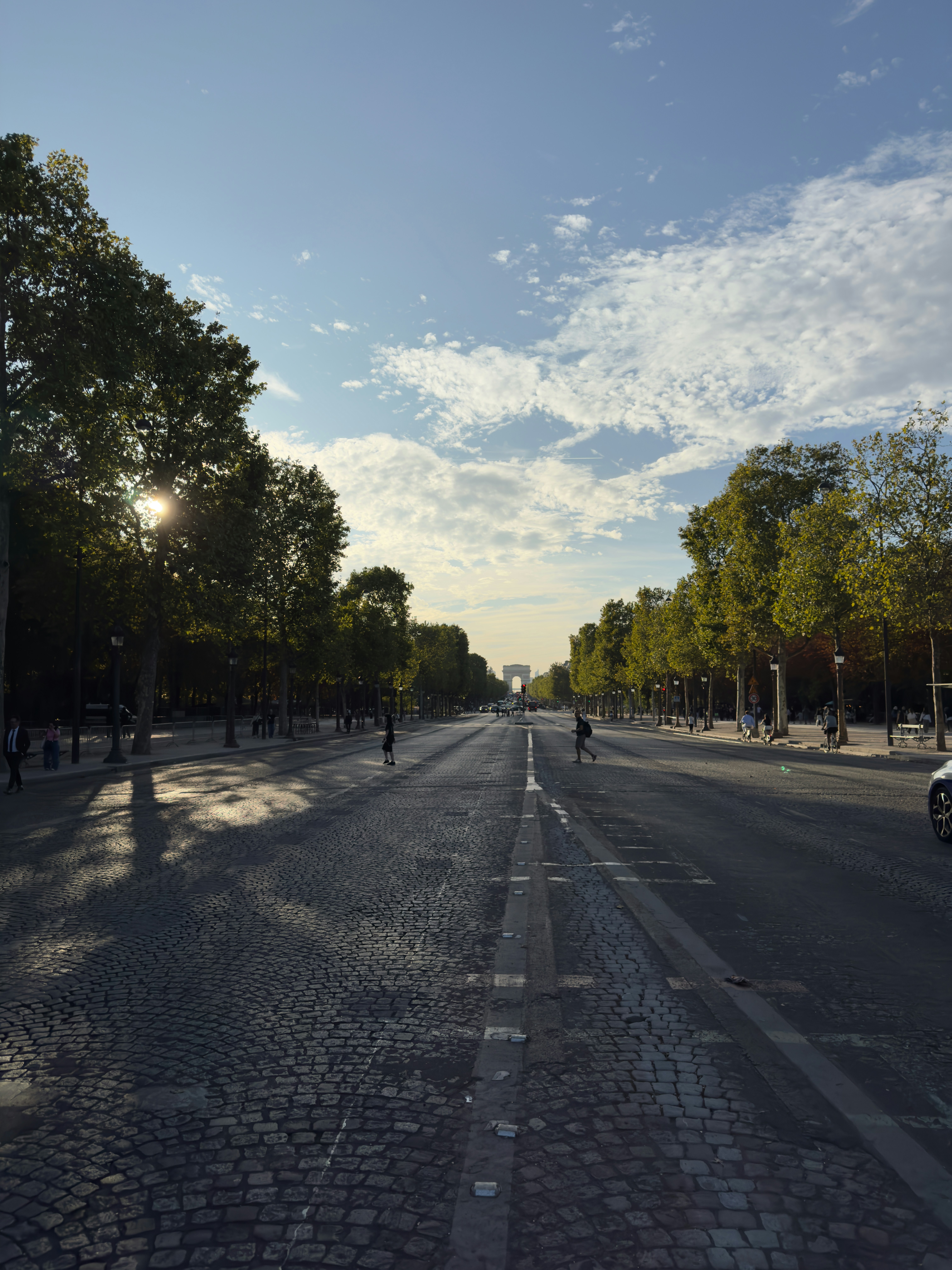 The Arc de Triomphe in the distance on a cobblestone avenue in Paris