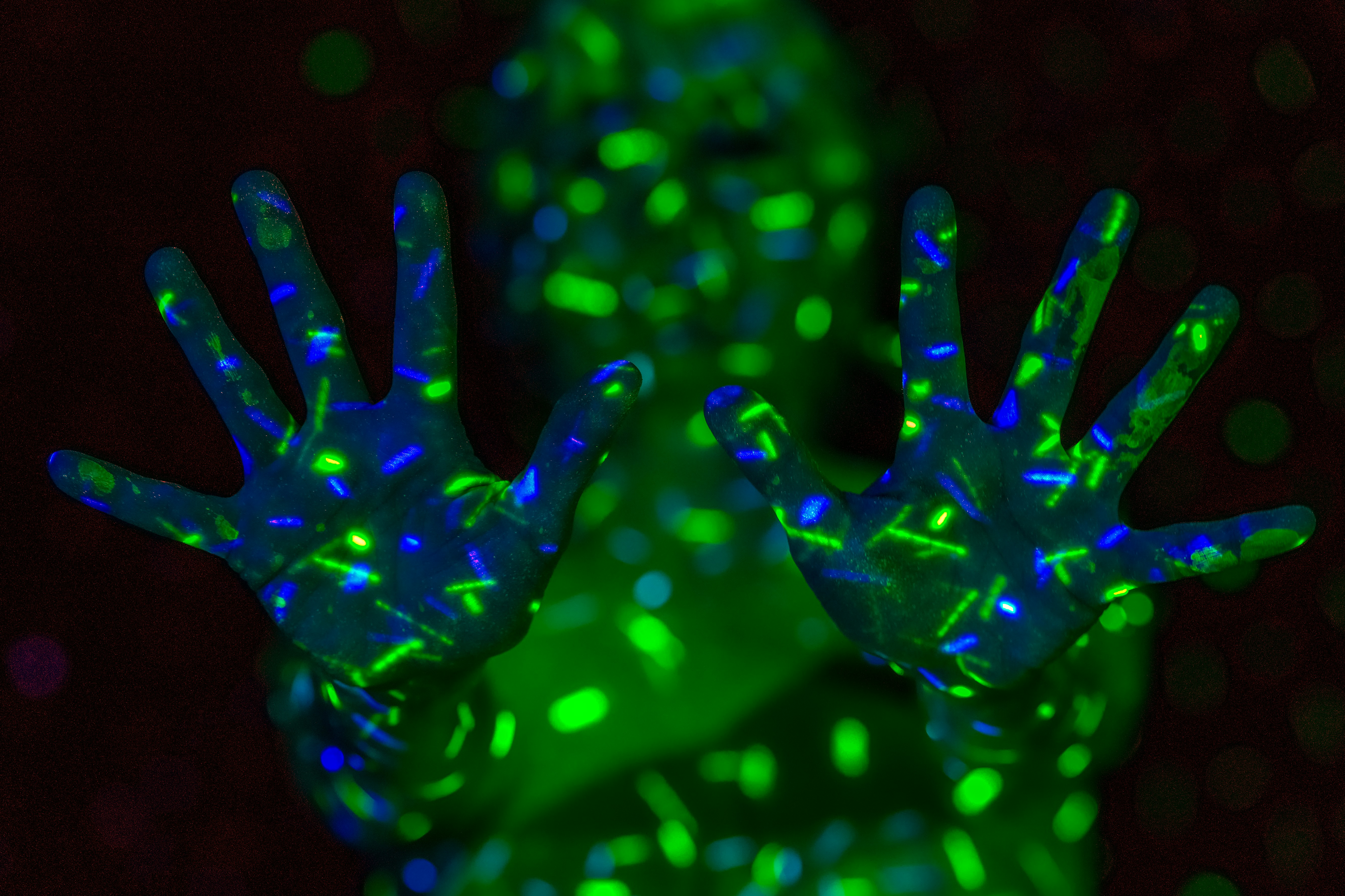 A person with glowing green and blue light patterns projected onto their hands