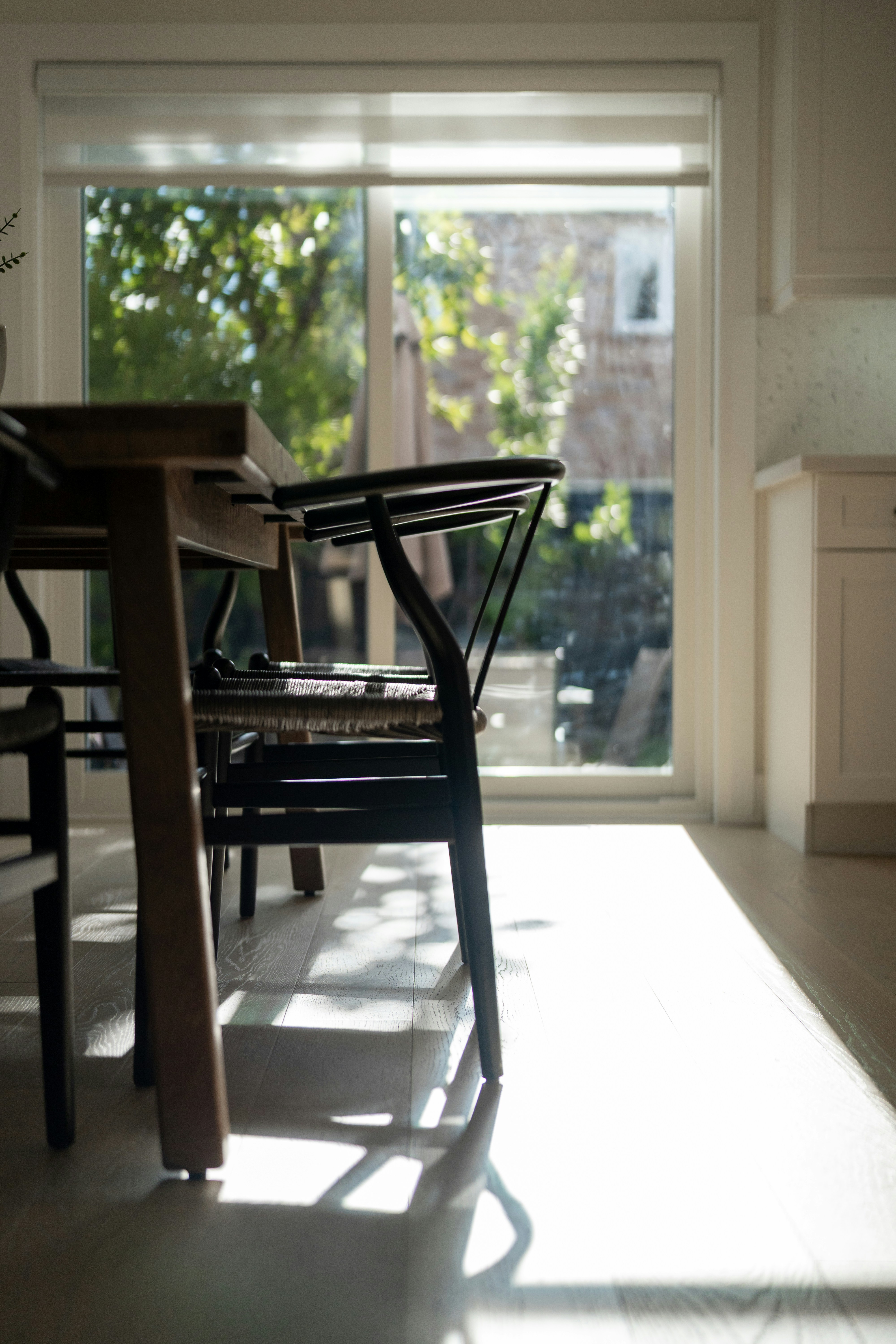 Black wooden chairs at a dining table in a sunlit room