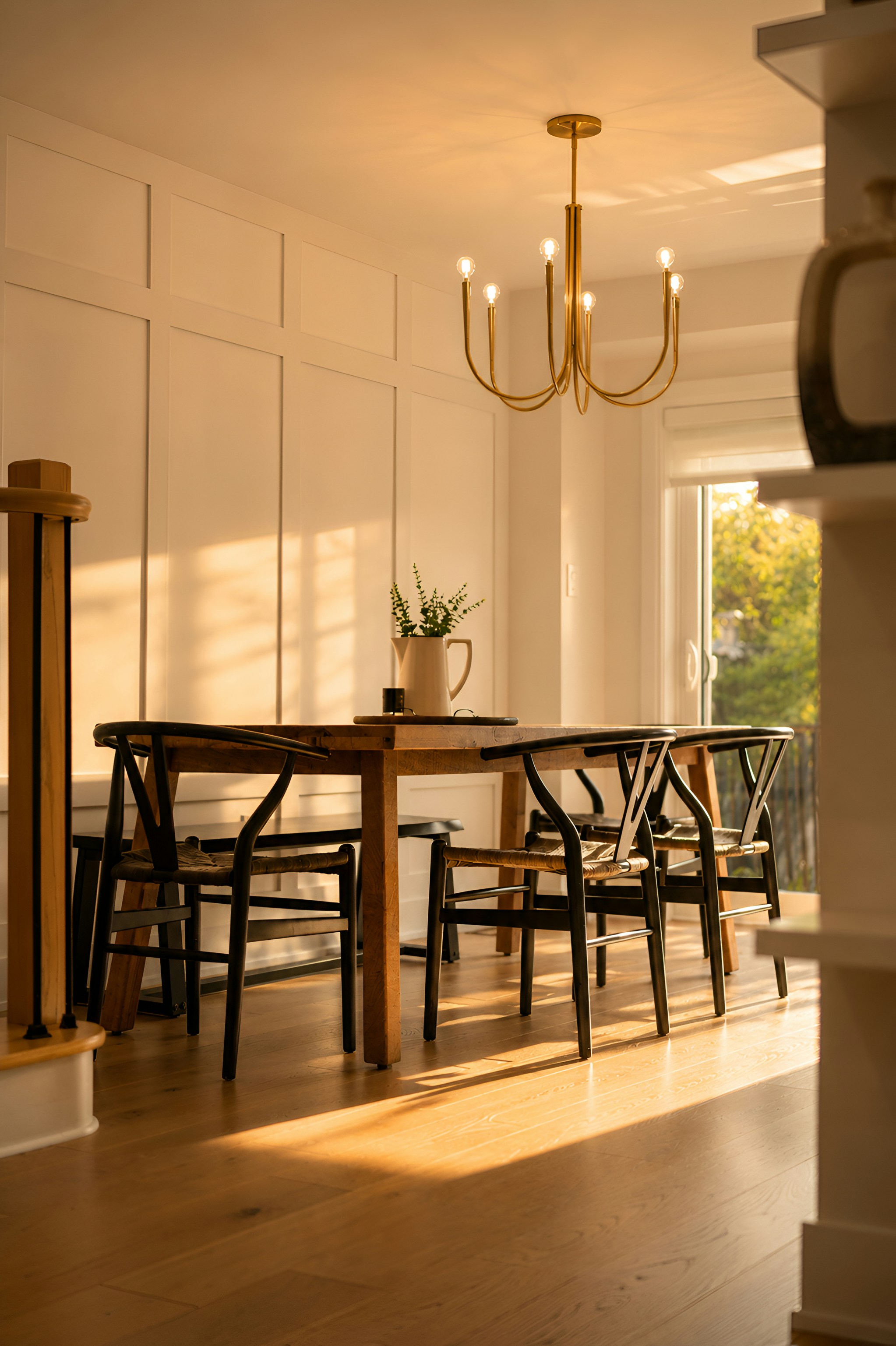 A wooden dining table with black chairs in a sunlit room