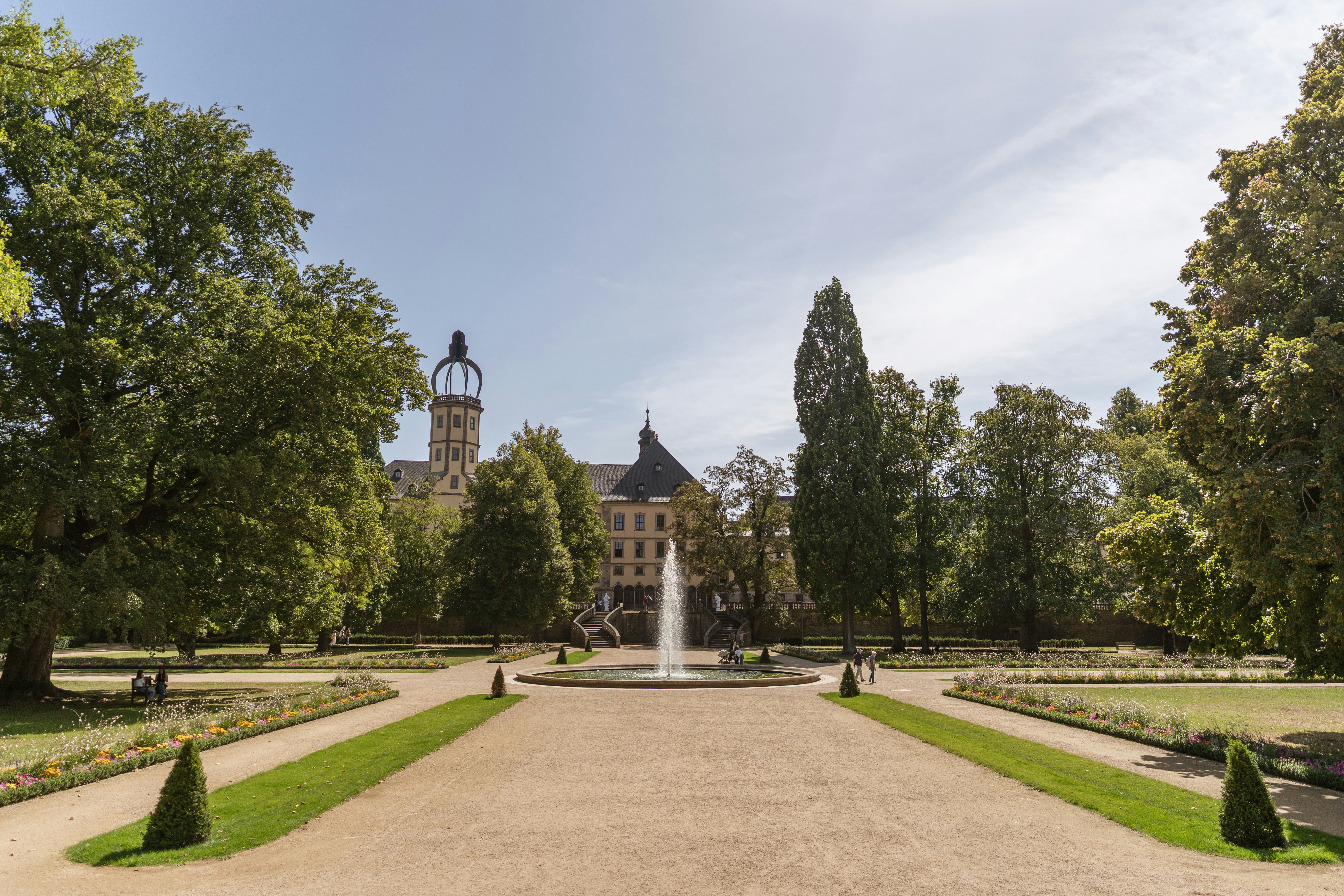 A fountain in a park with a large building in the background