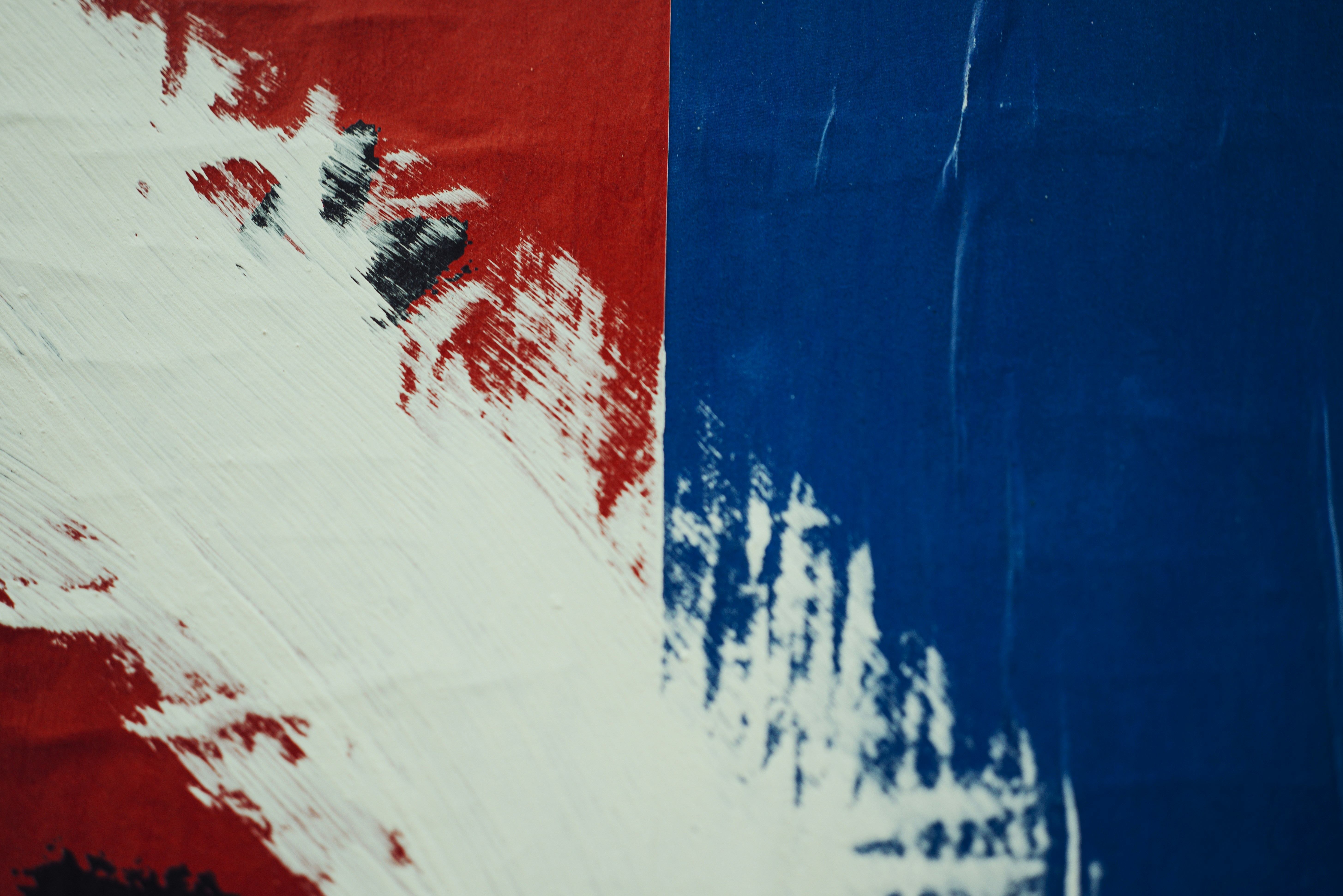 White paint strokes over a split red and blue background