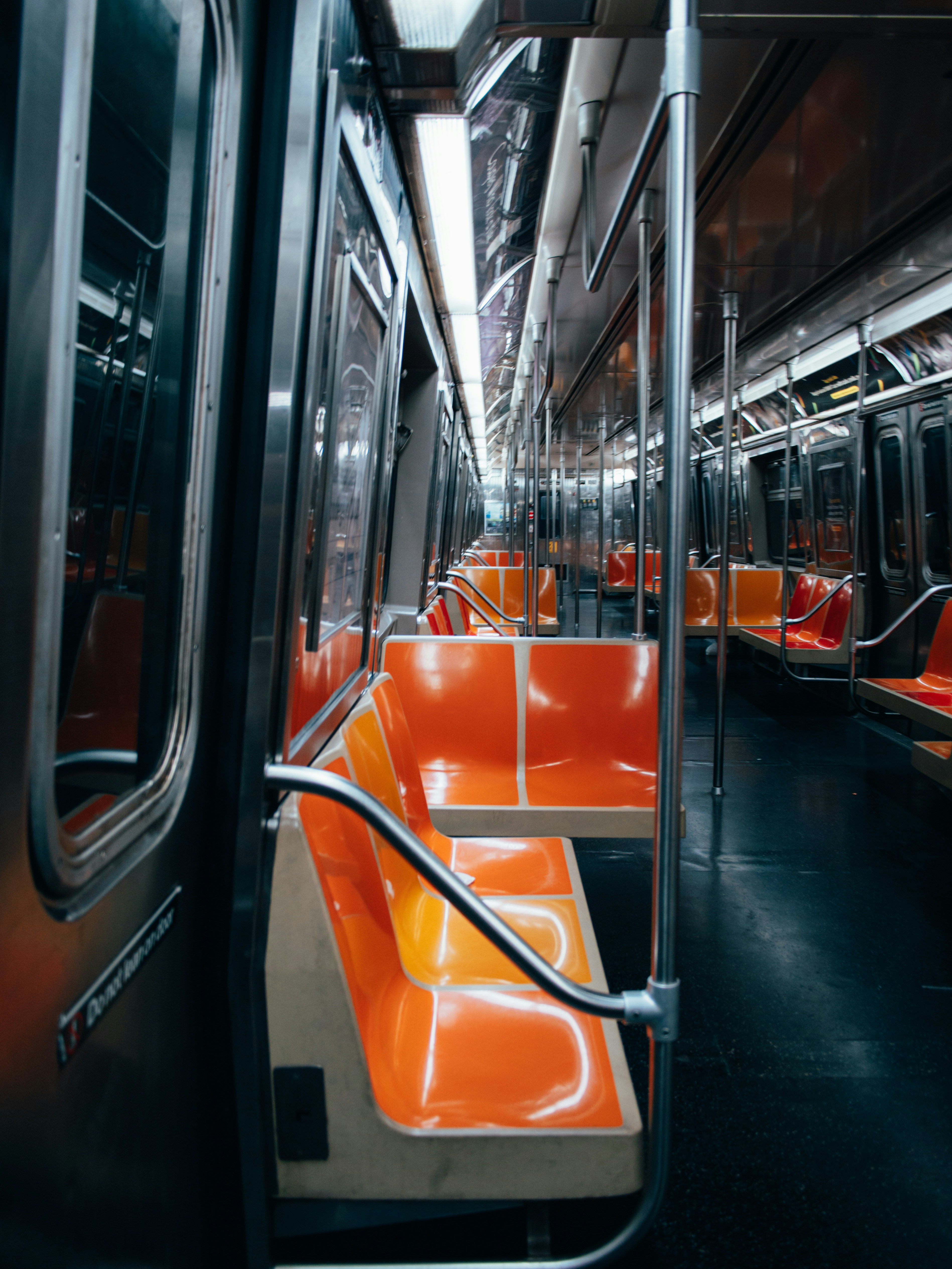 Empty orange plastic seats inside a brightly lit subway car