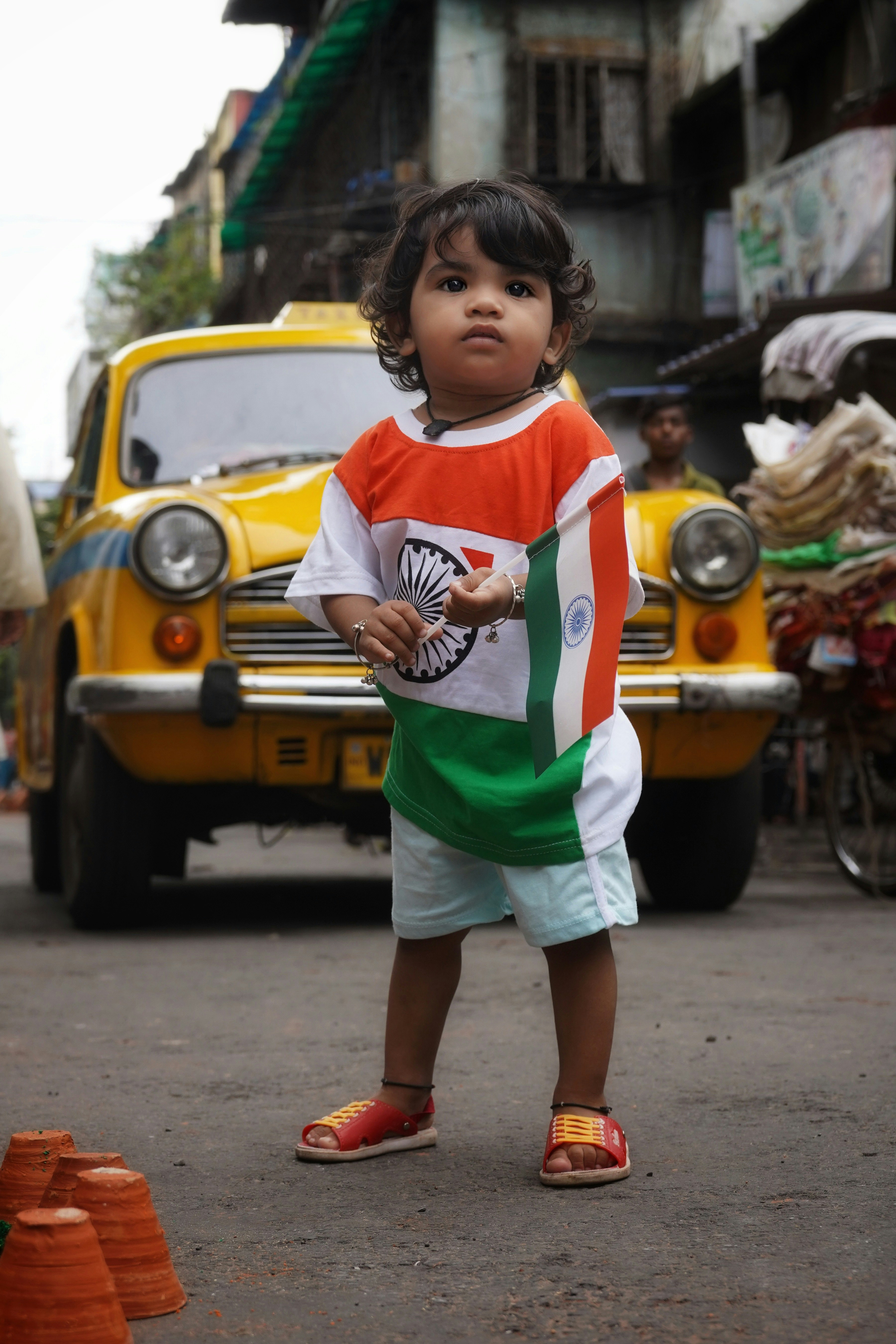 A toddler wearing an Indian flag shirt holding a small flag in Kolkata