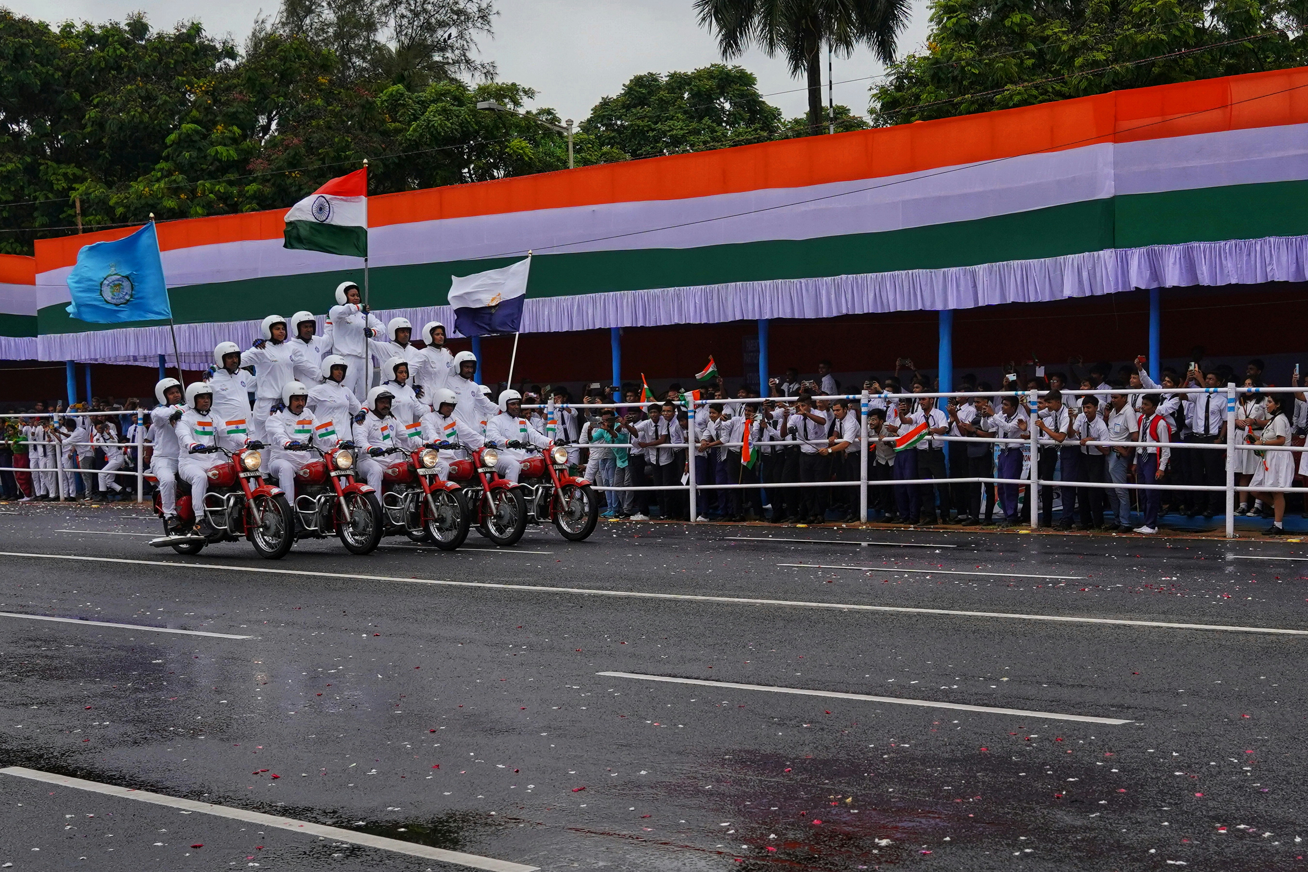 A group of people in white uniforms performing motorcycle stunts during an Indian parade