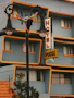 A street lamp with colorful ribbons before a blue hotel with yellow trim