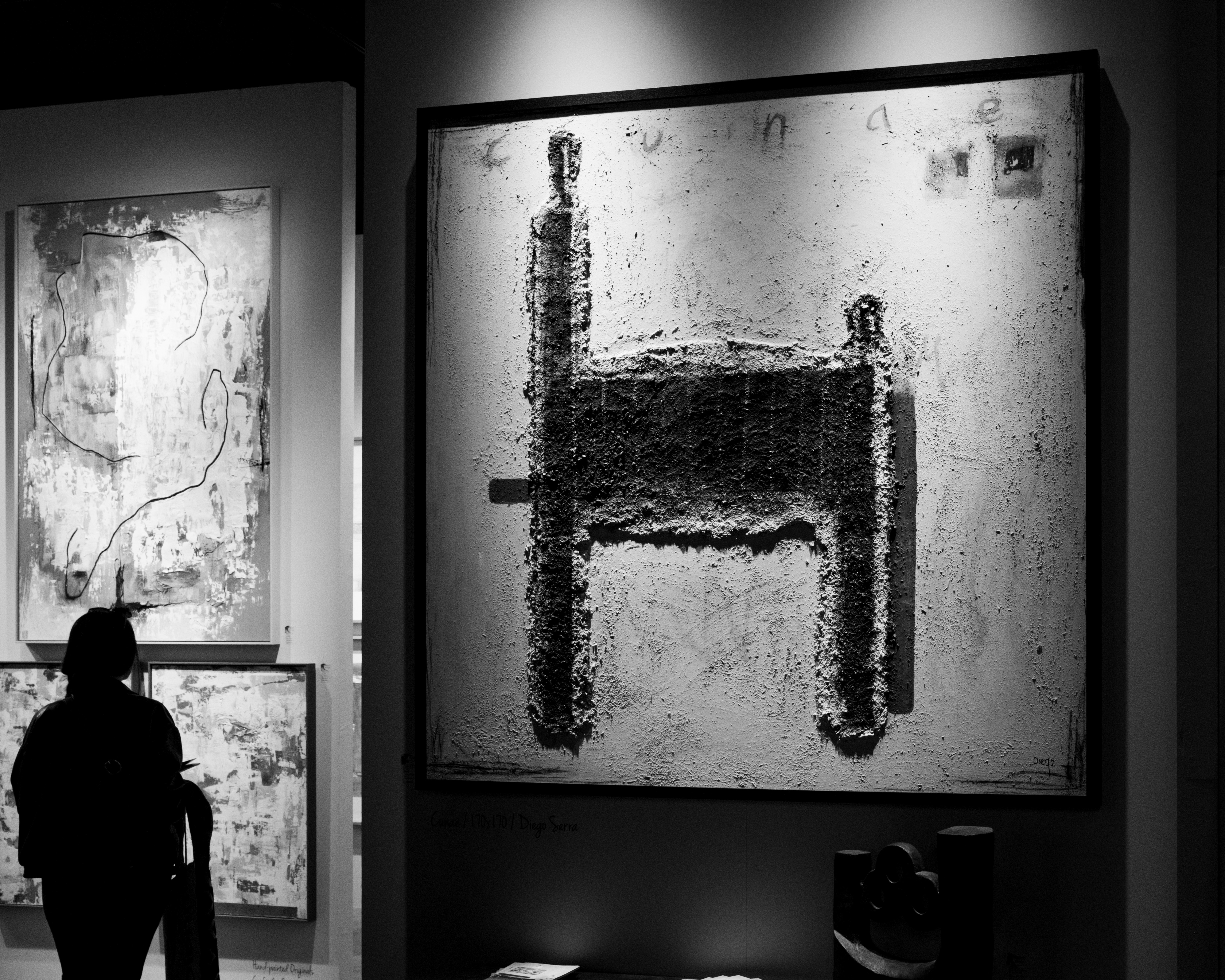 Person in silhouette viewing a textured artwork
