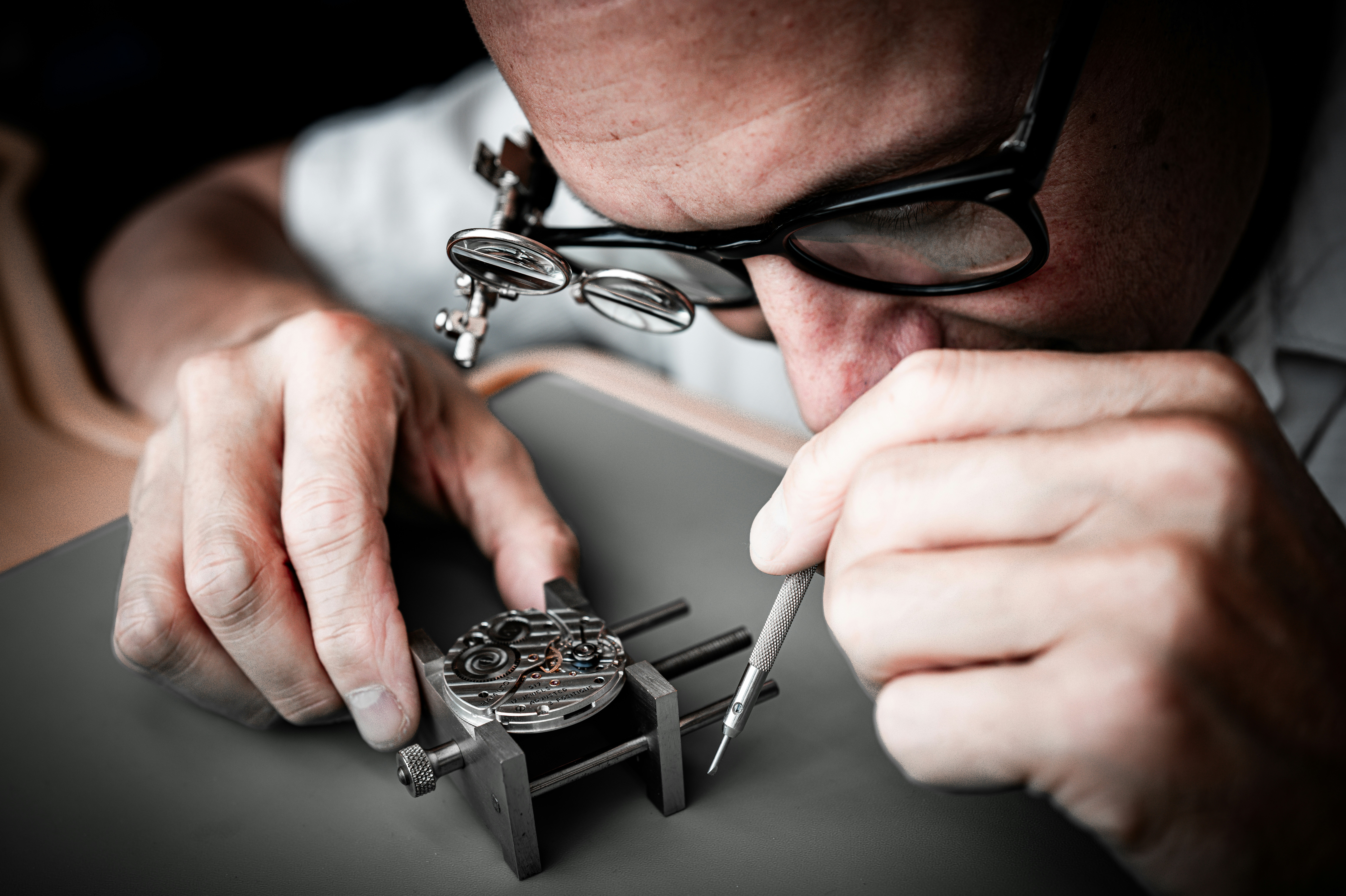 A watchmaker using a precision tool to repair a mechanical watch movement