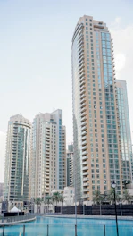 Modern glass skyscrapers reflecting the sky above a calm blue canal in Dubai