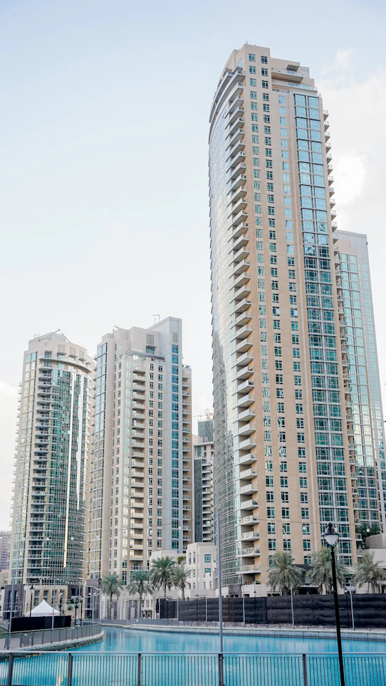 Modern glass skyscrapers reflecting the sky above a calm blue canal in Dubai