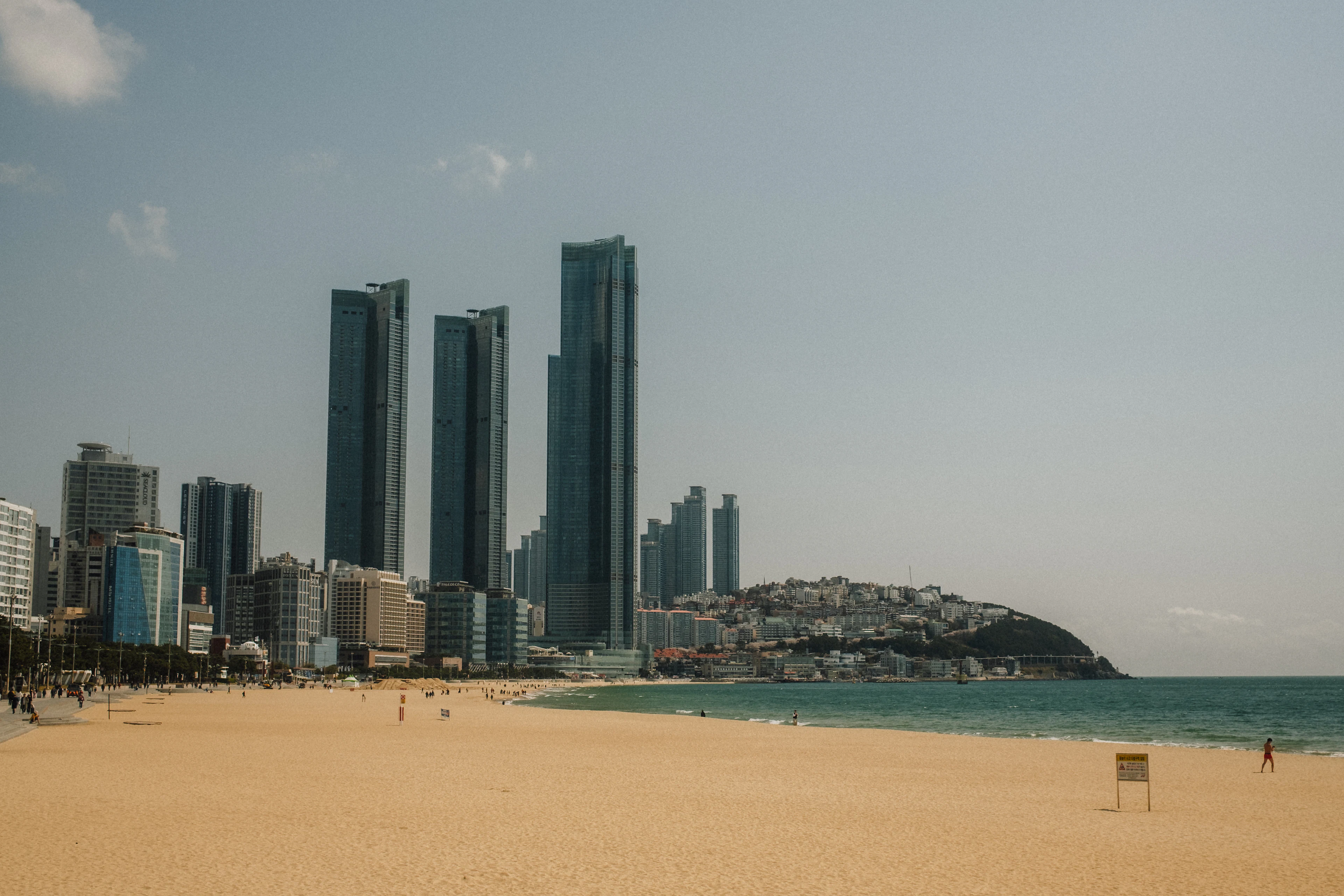 A wide sandy beach and high-rise towers beside the sea in Busan