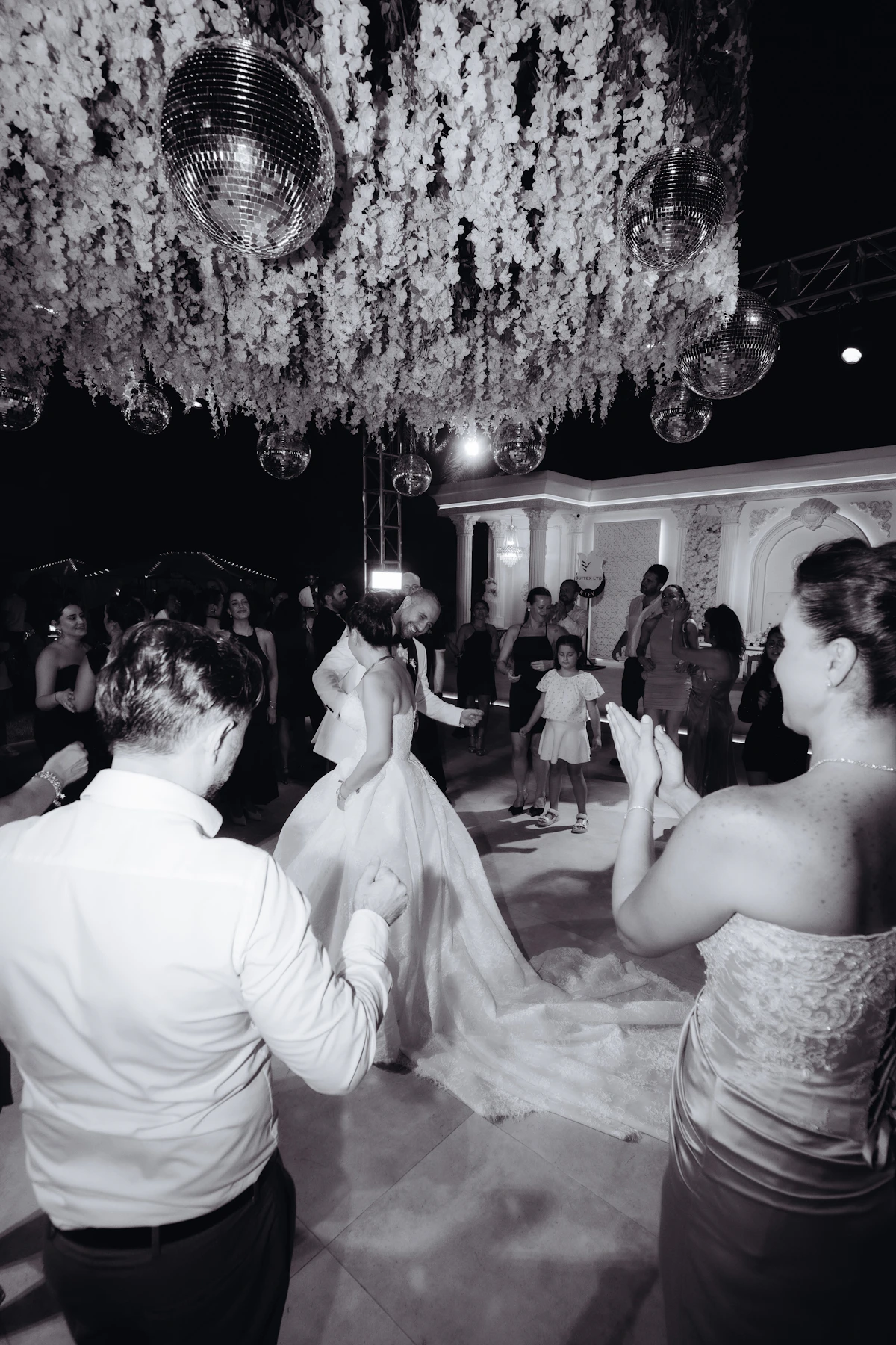 Bride and groom dancing beneath wedding flowers and lights