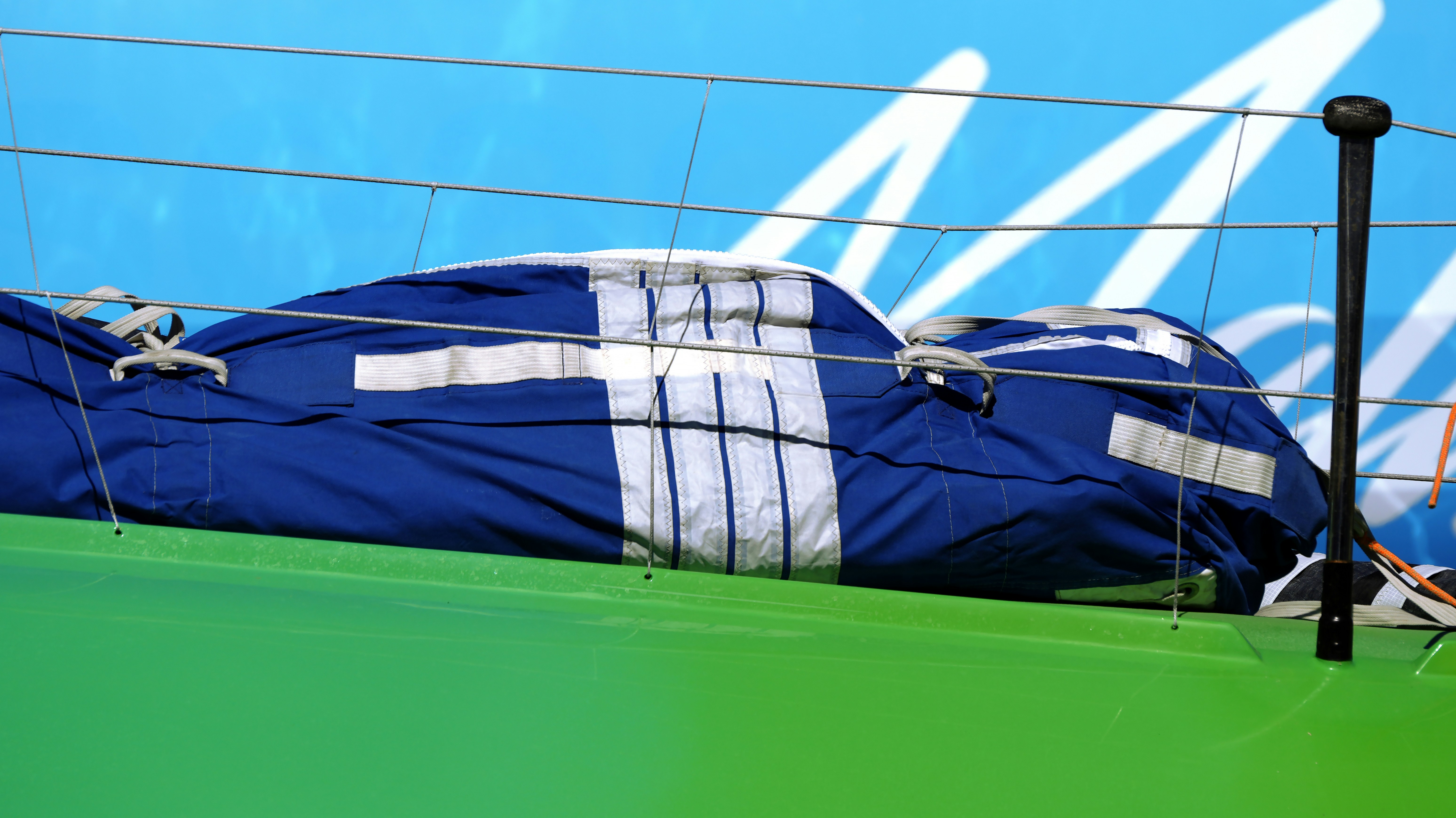 A blue sail cover with white stripes on a green boat deck