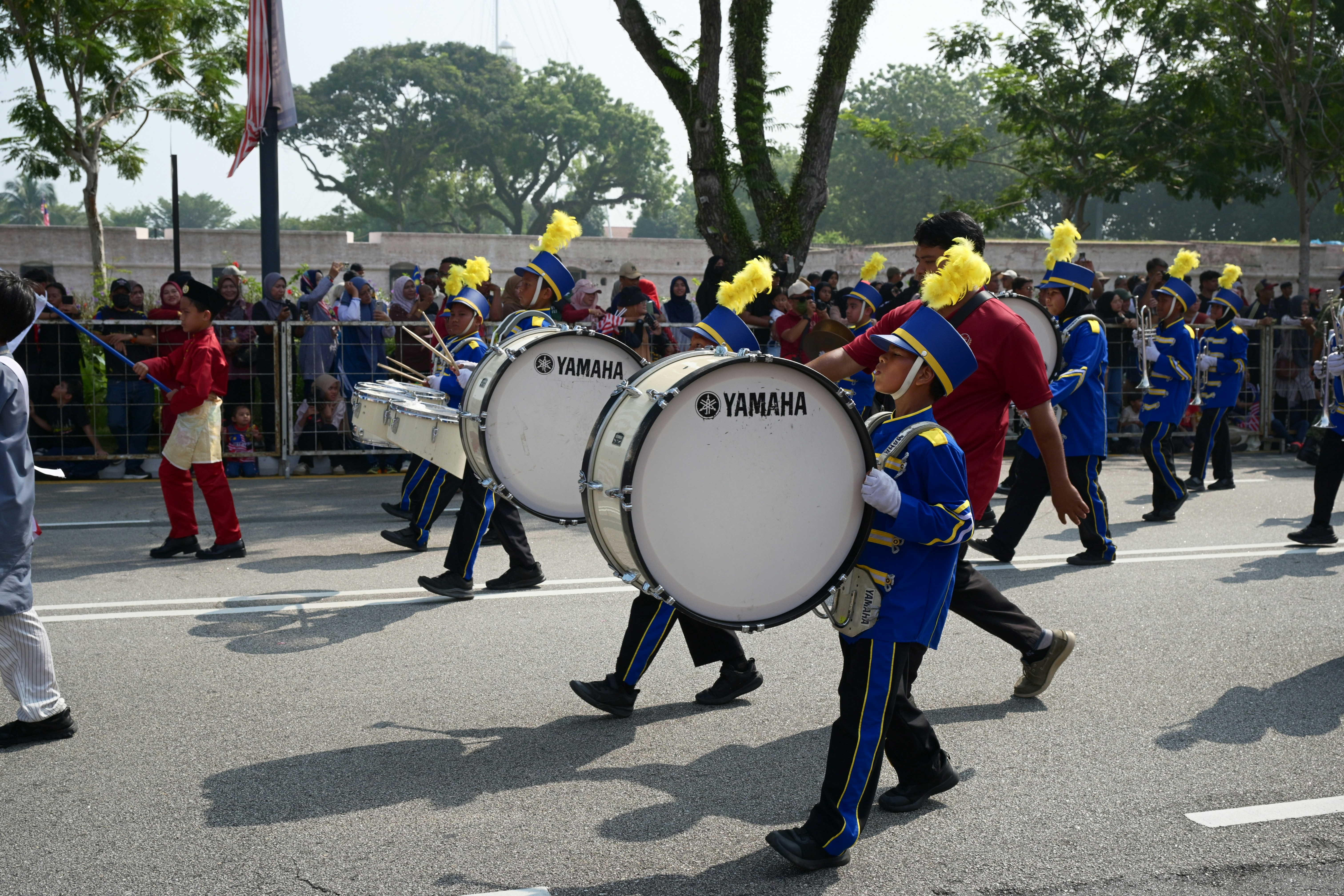 A marching band with children in blue uniforms playing drums on a city street
