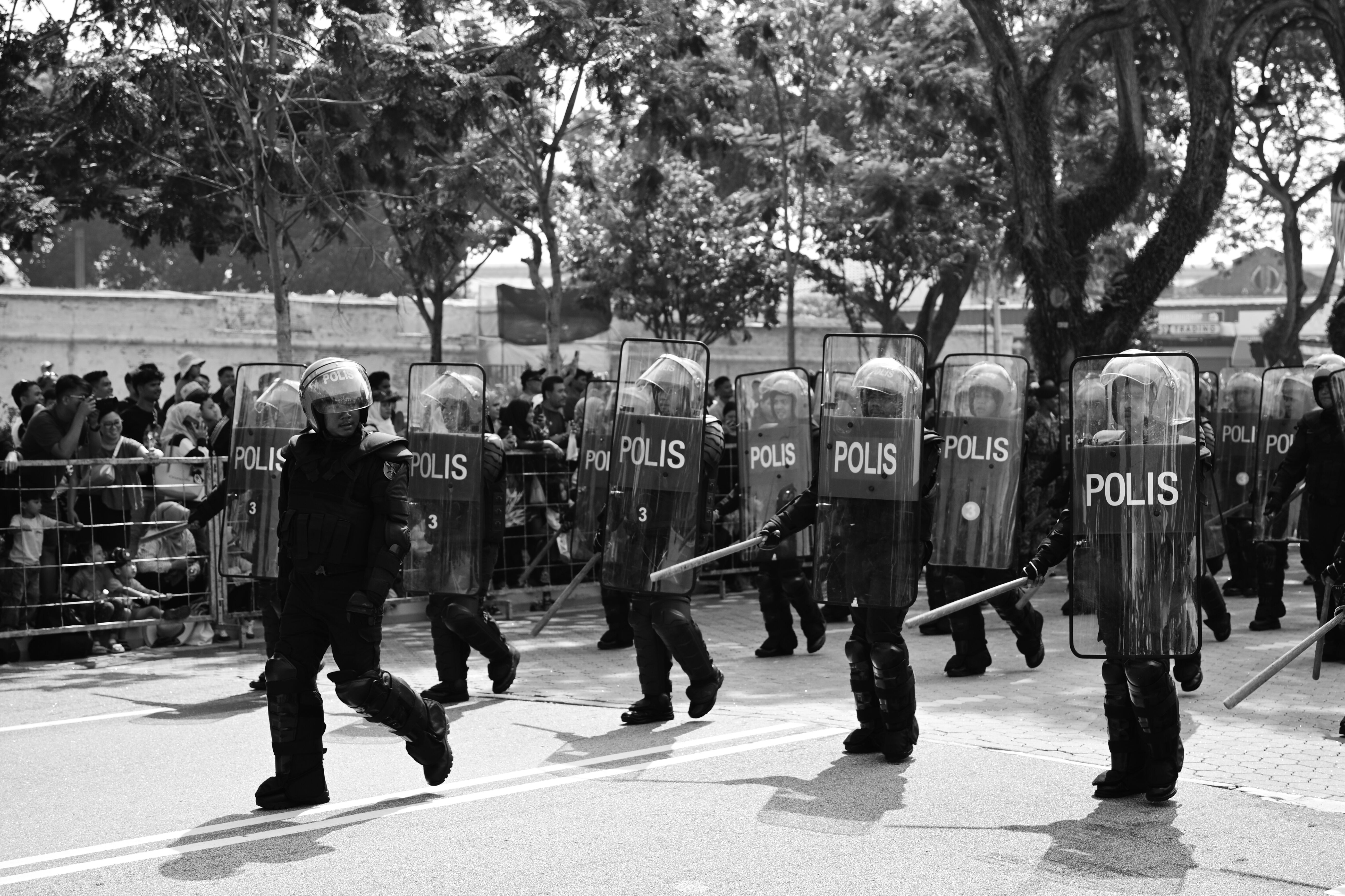 Police officers in riot gear with shields walking along a city street