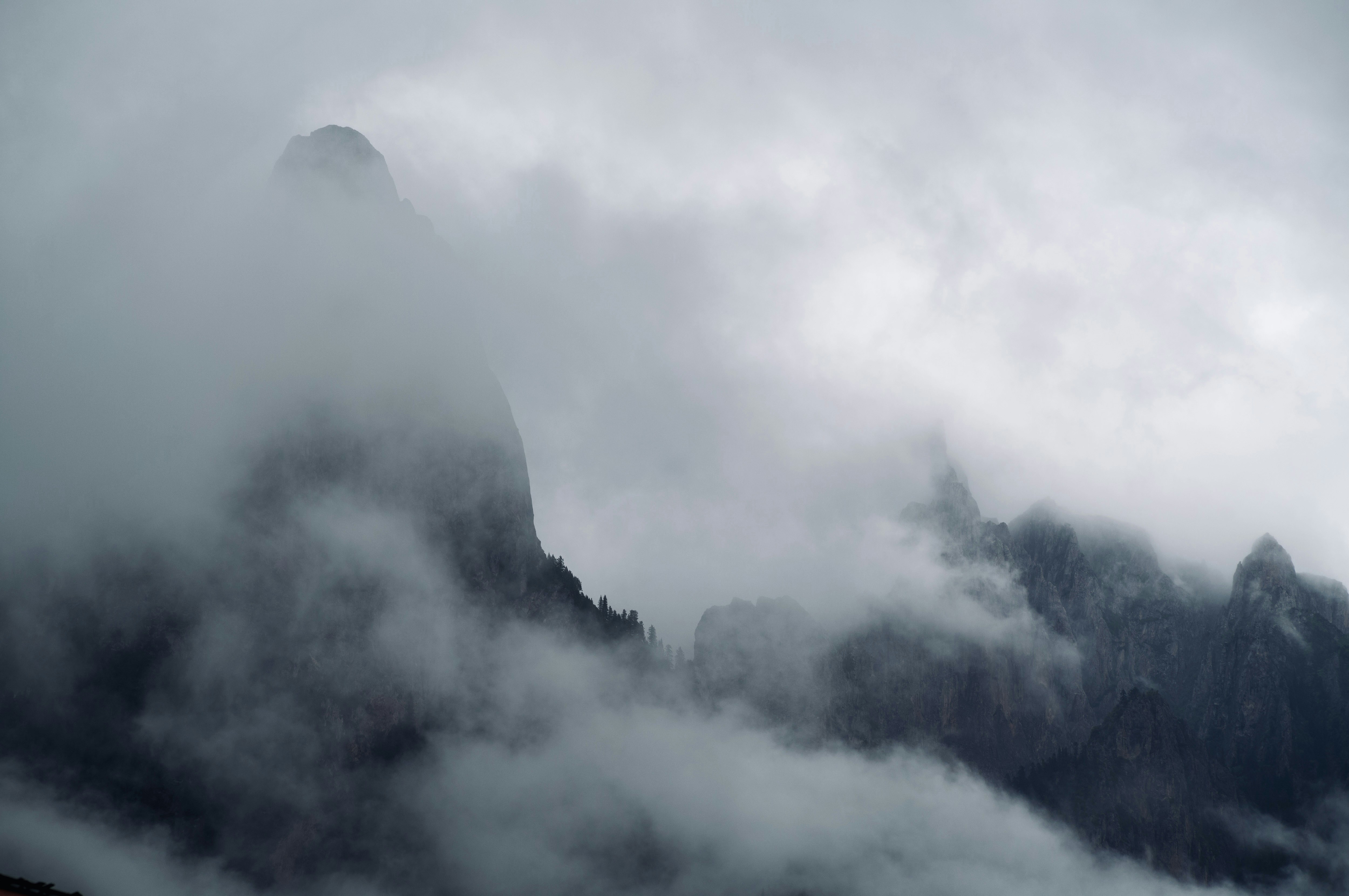 Jagged mountain peaks partially obscured by thick grey mist and low clouds