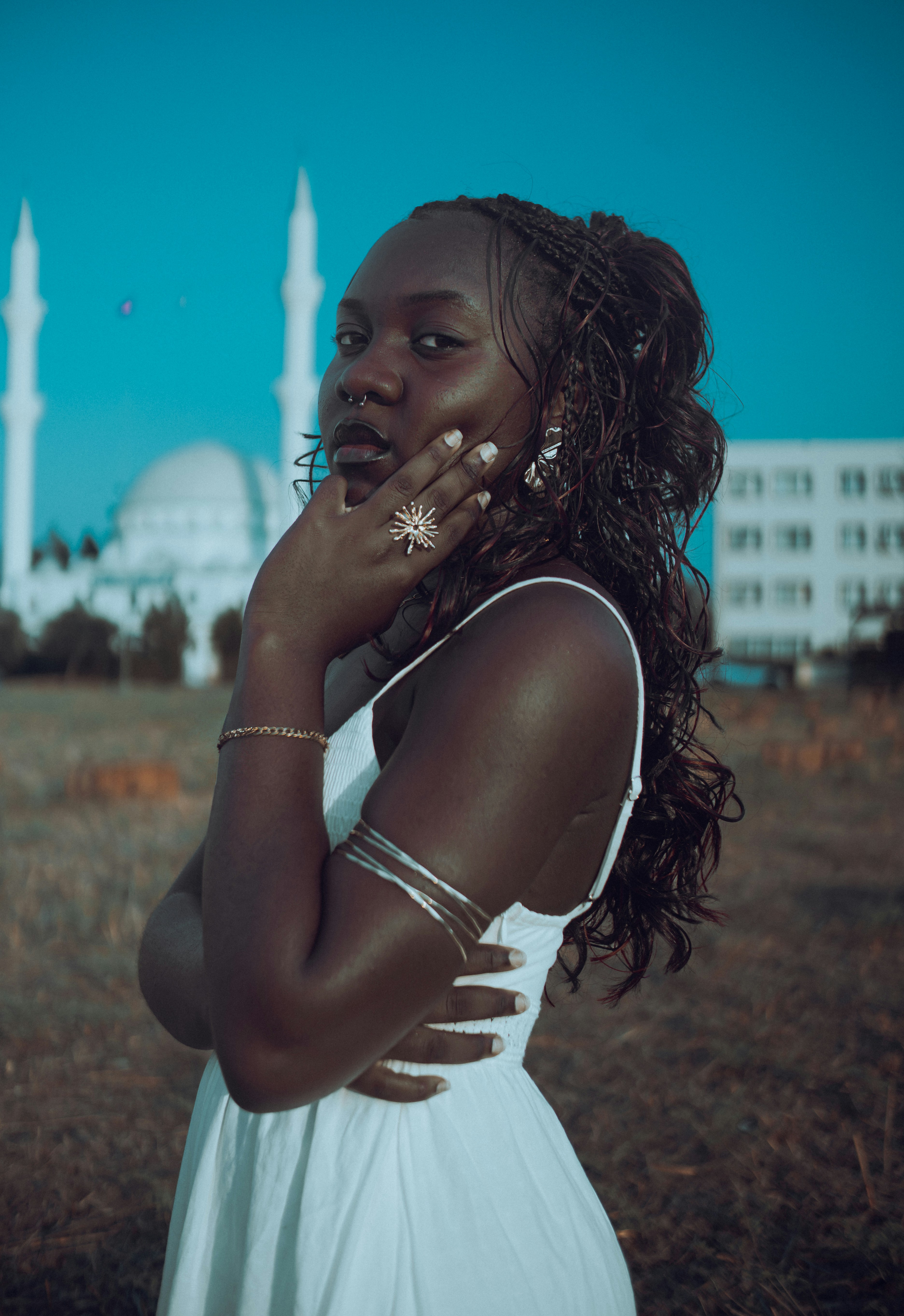A woman in a white dress with a mosque in the background