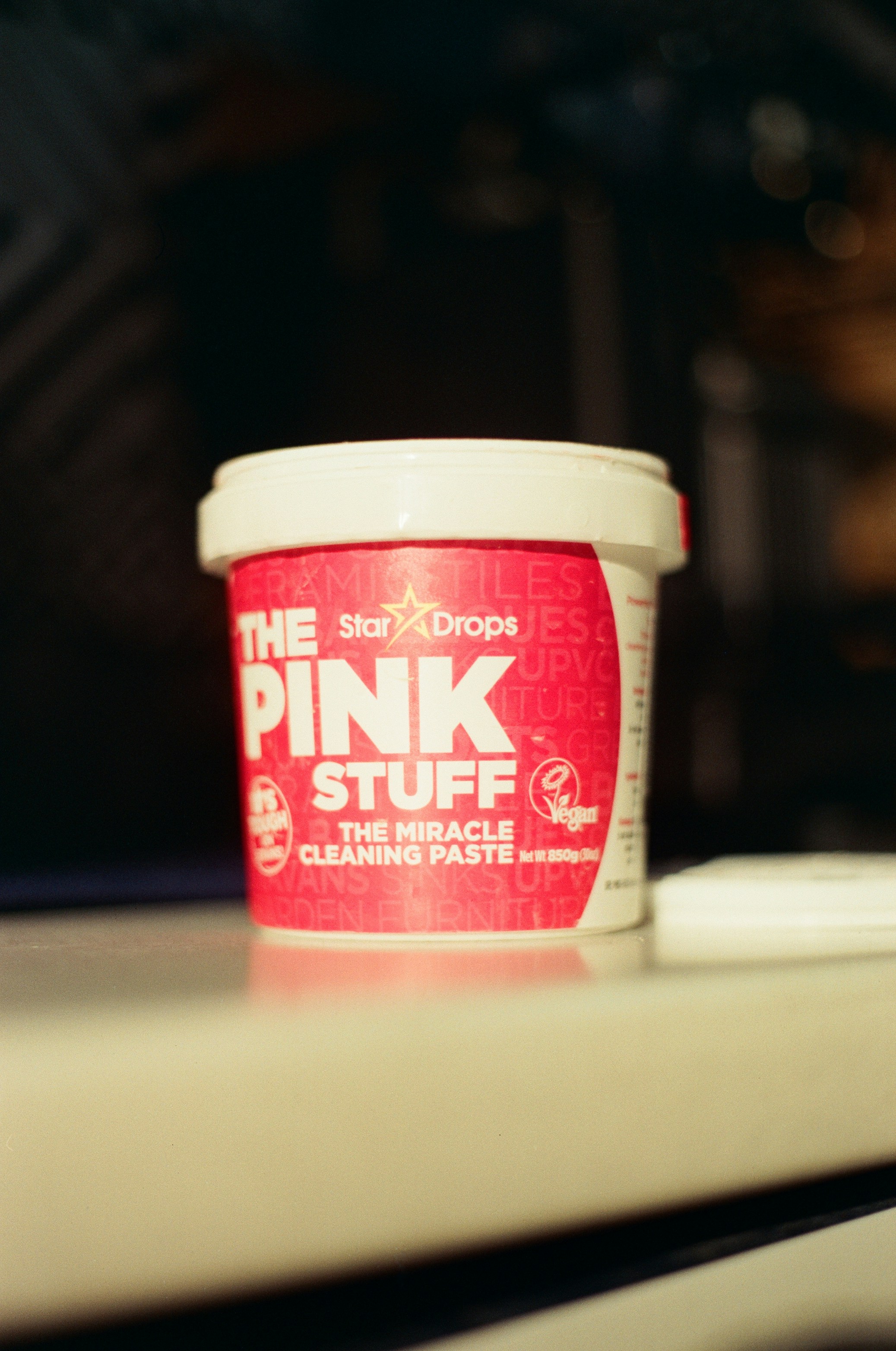 A tub of The Pink Stuff cleaning paste on a white surface