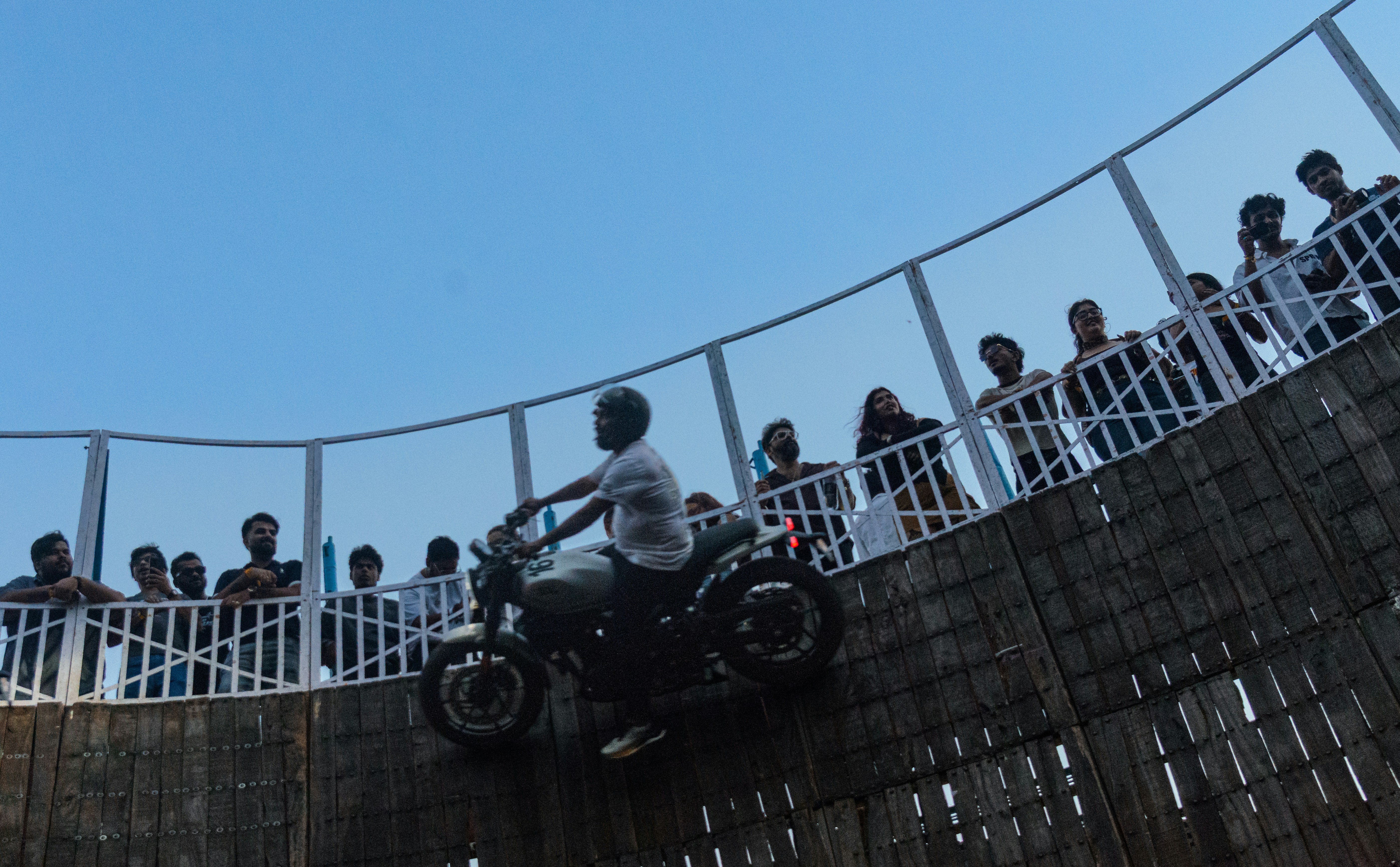 A motorcyclist riding on the vertical wooden wall of a well of death