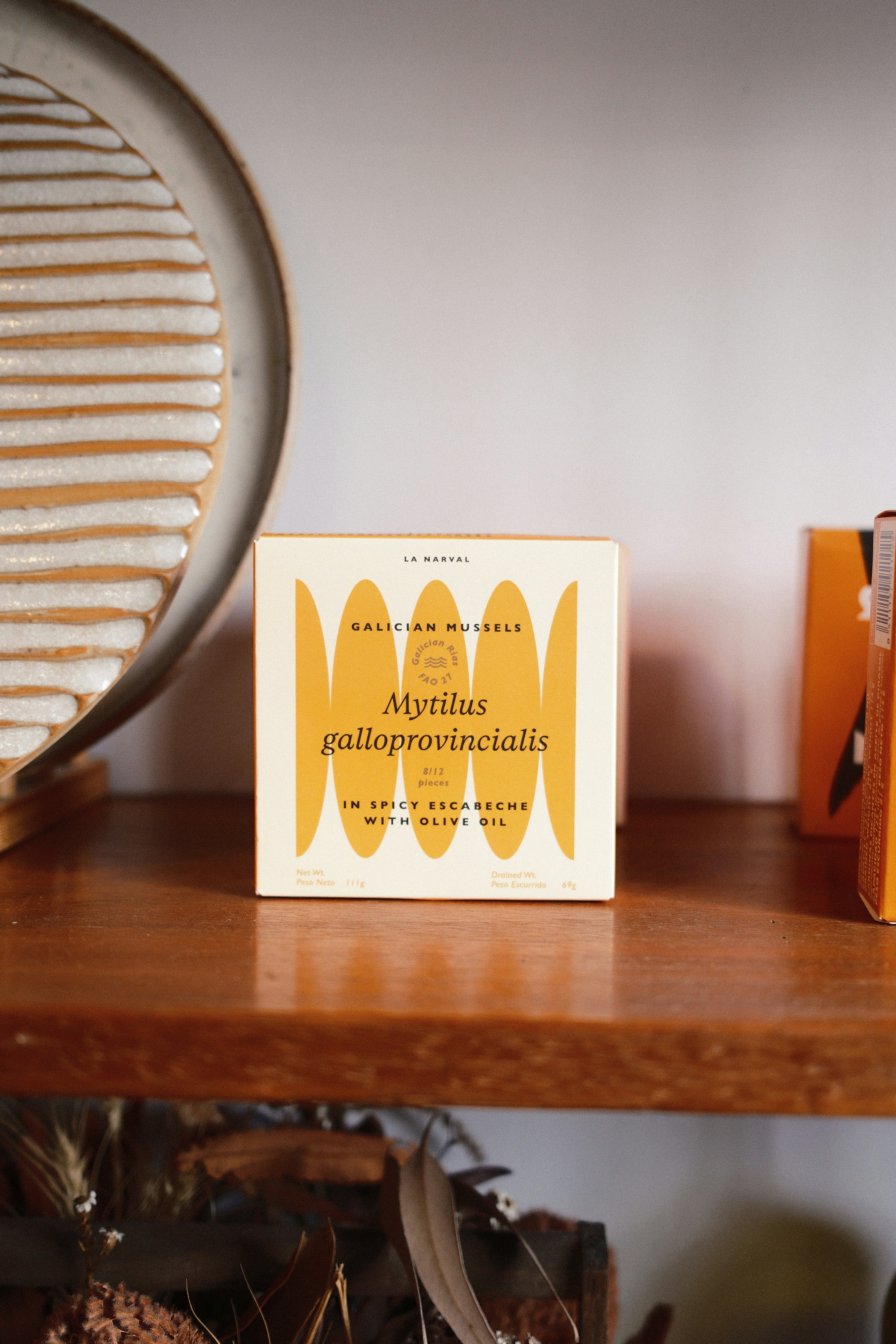 A box of Galician mussels in spicy escabeche on a wooden shelf