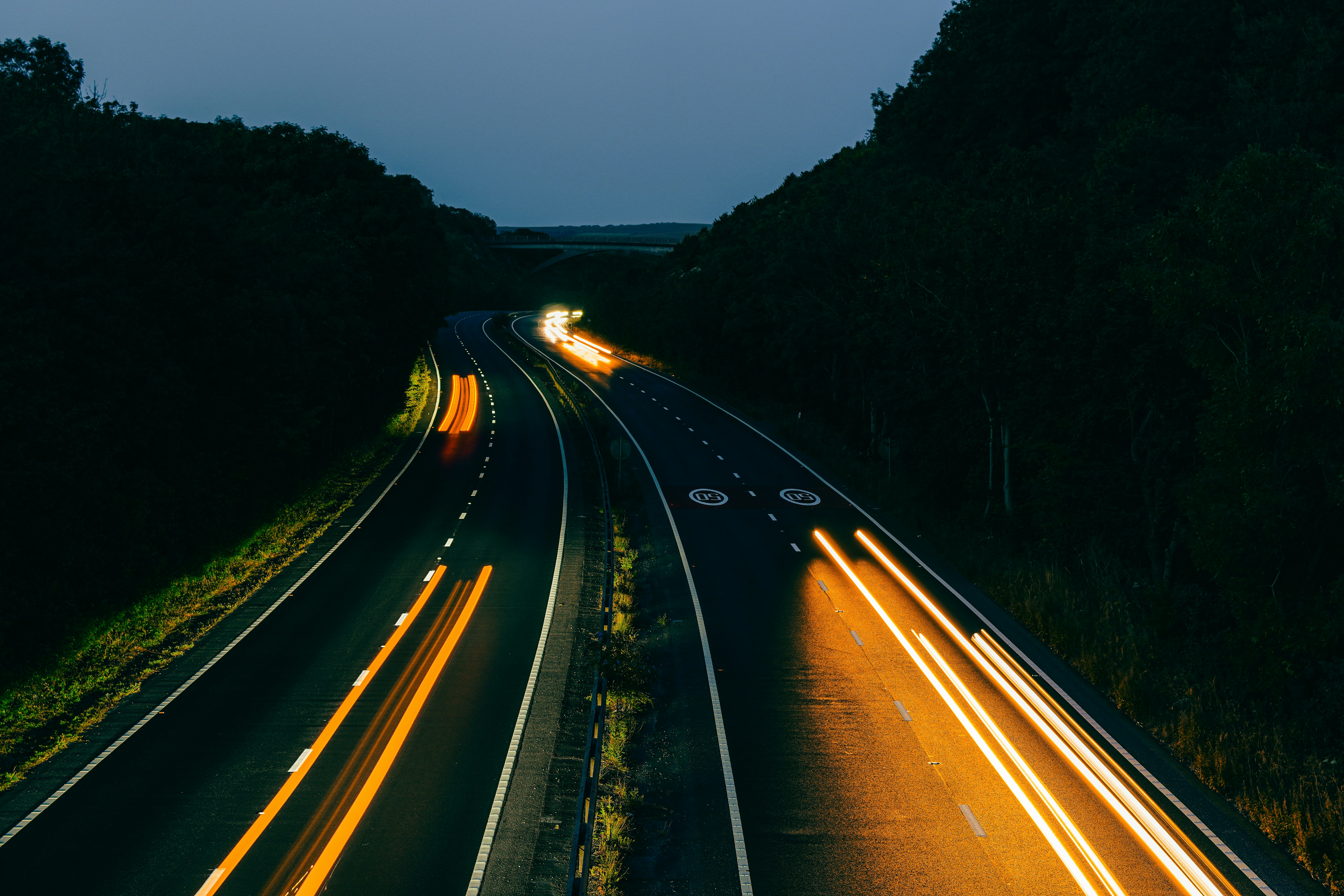 Long exposure light trails from vehicles on a dark highway at night