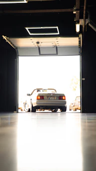 A silver Mercedes-Benz convertible parked in a bright garage doorway