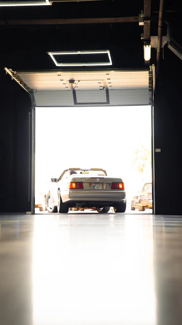 A silver Mercedes-Benz convertible parked in a bright garage doorway
