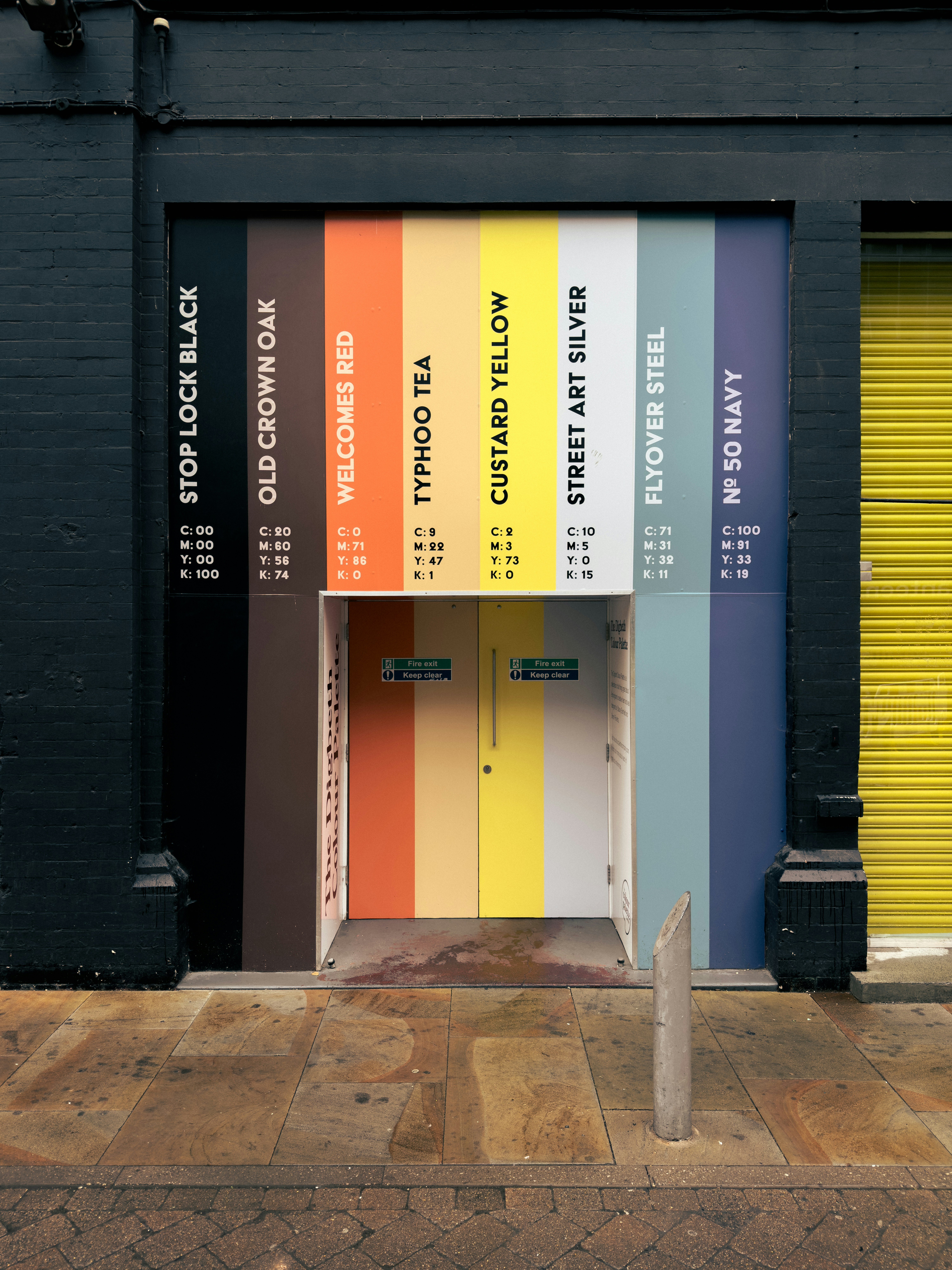 A colorful wall display of paint swatches with names and CMYK values above a doorway