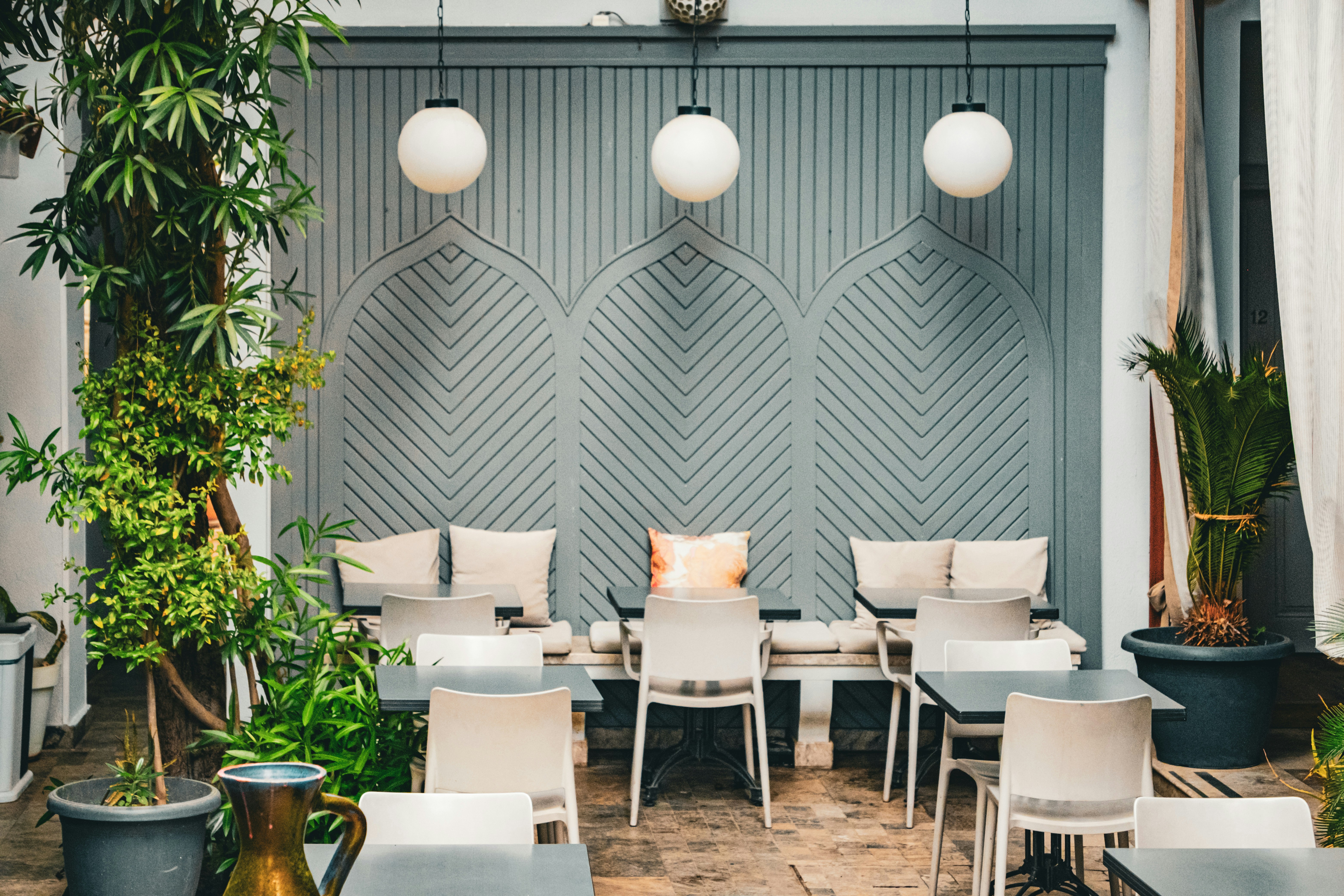 Tables et chaises dans une terrasse avec un mur à panneaux gris et des globes lumineux