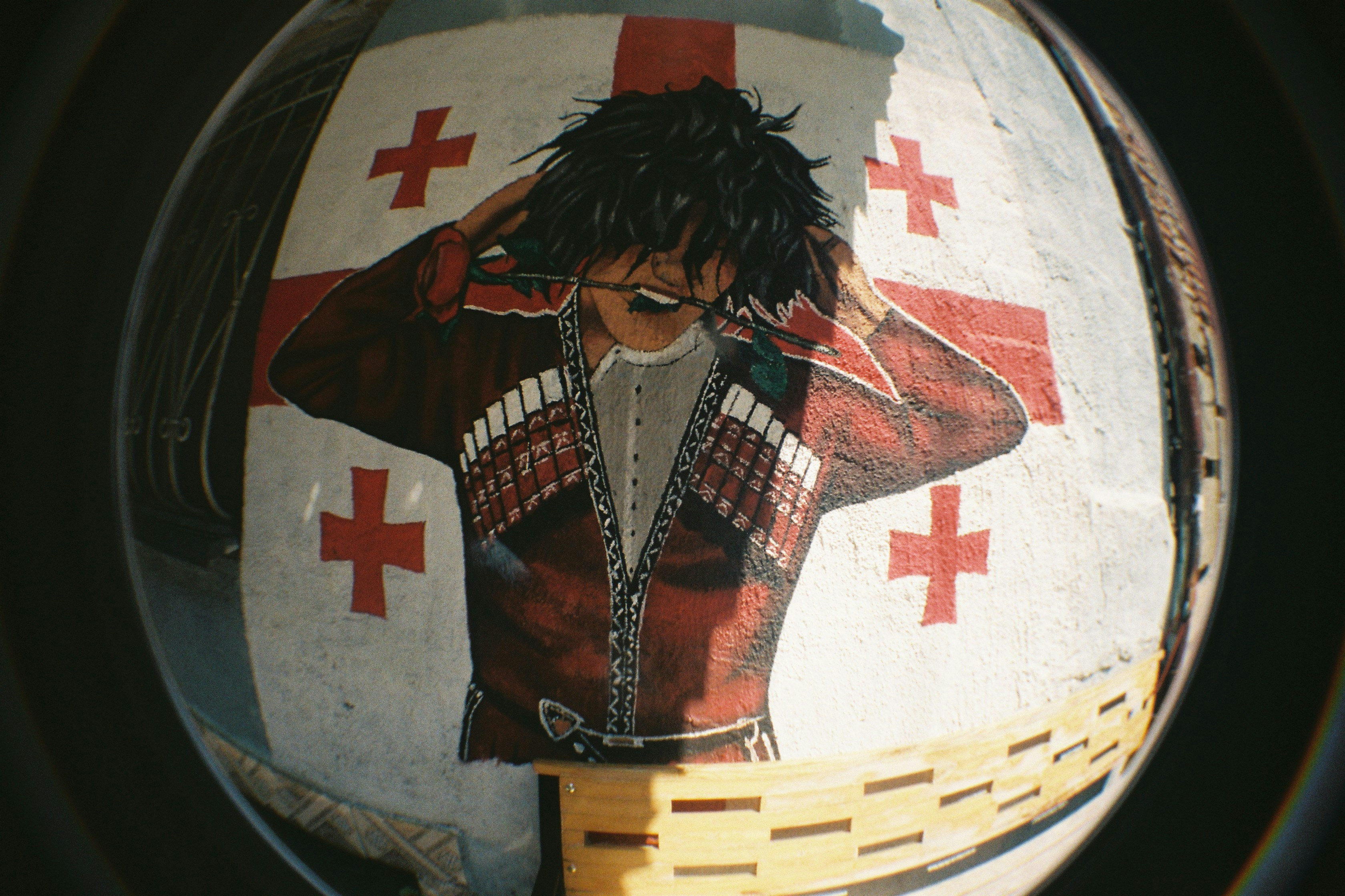 A mural of a person in traditional Georgian clothing holding a rose in their mouth