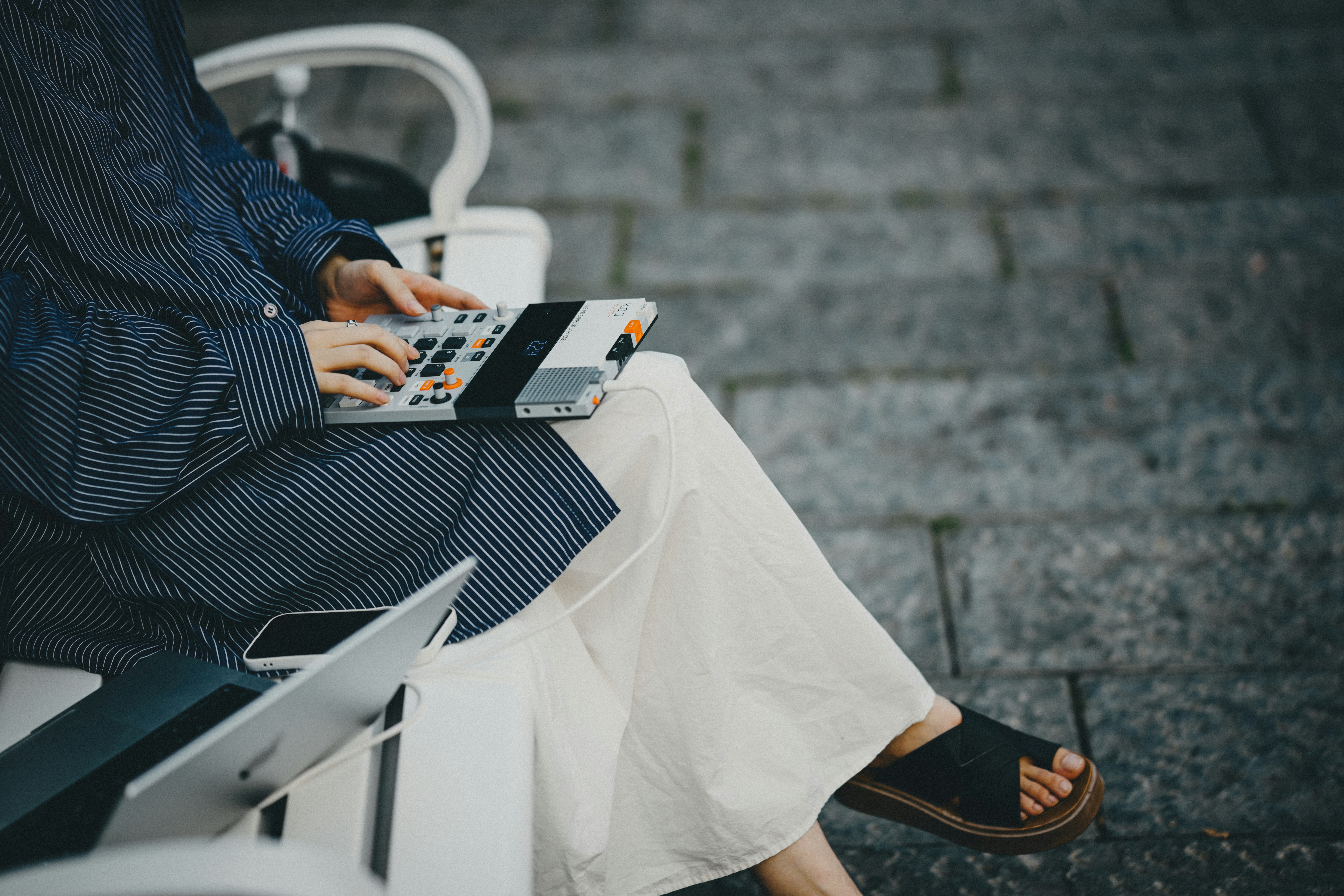 A person in a striped shirt using a portable sampler on a bench