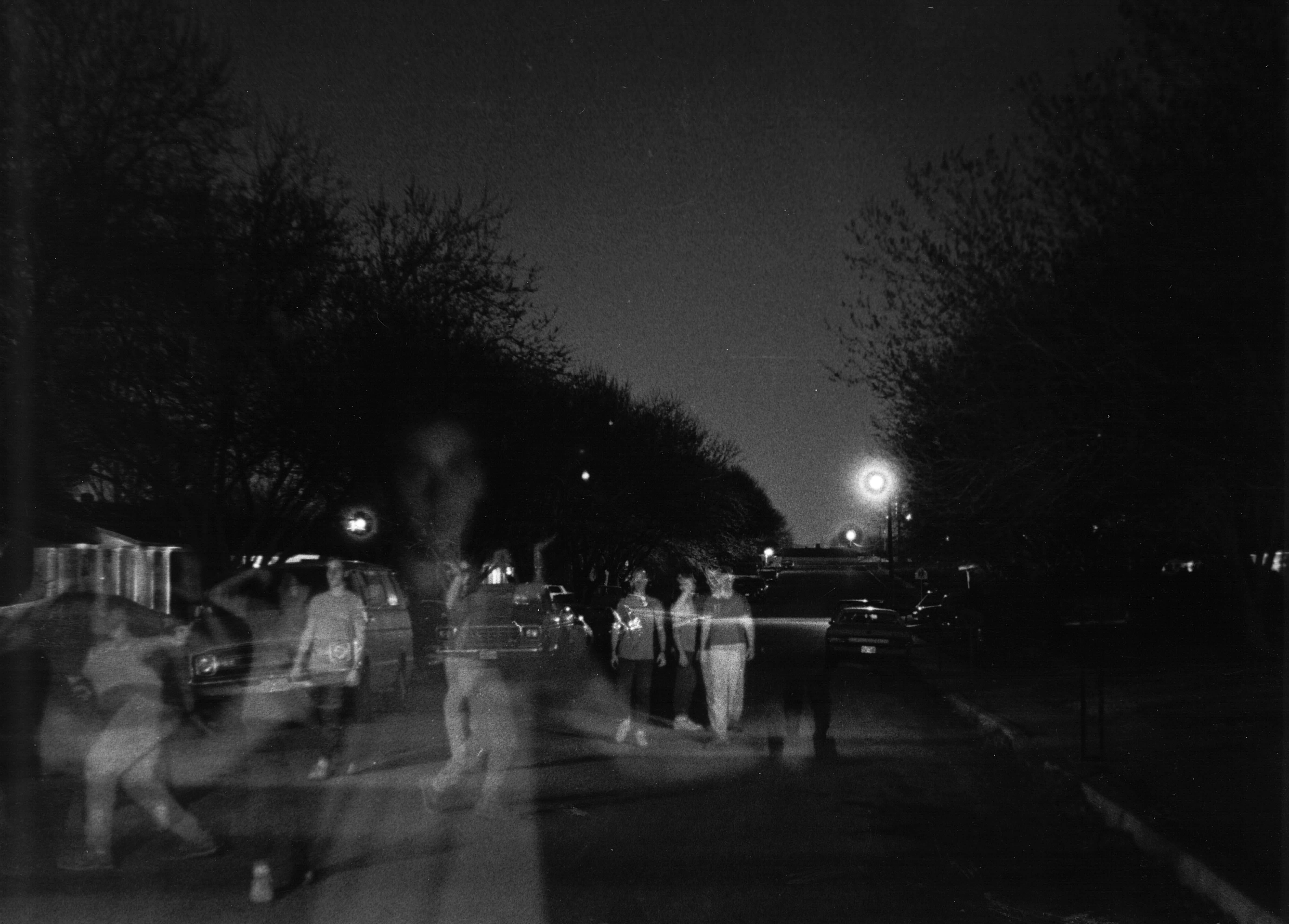 A group of people walking on a dark suburban street at night