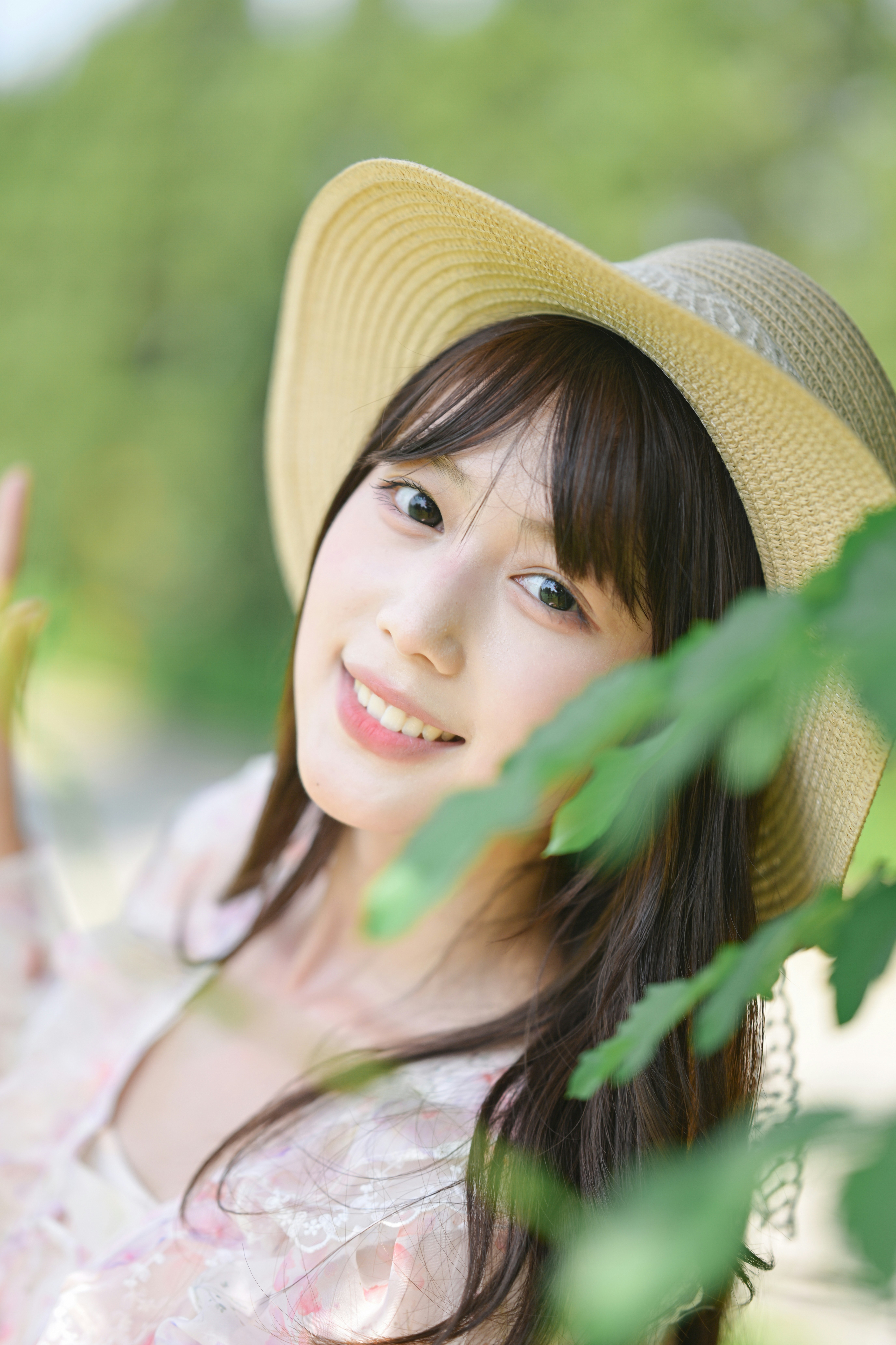 A smiling woman wearing a straw hat in a sunlit garden