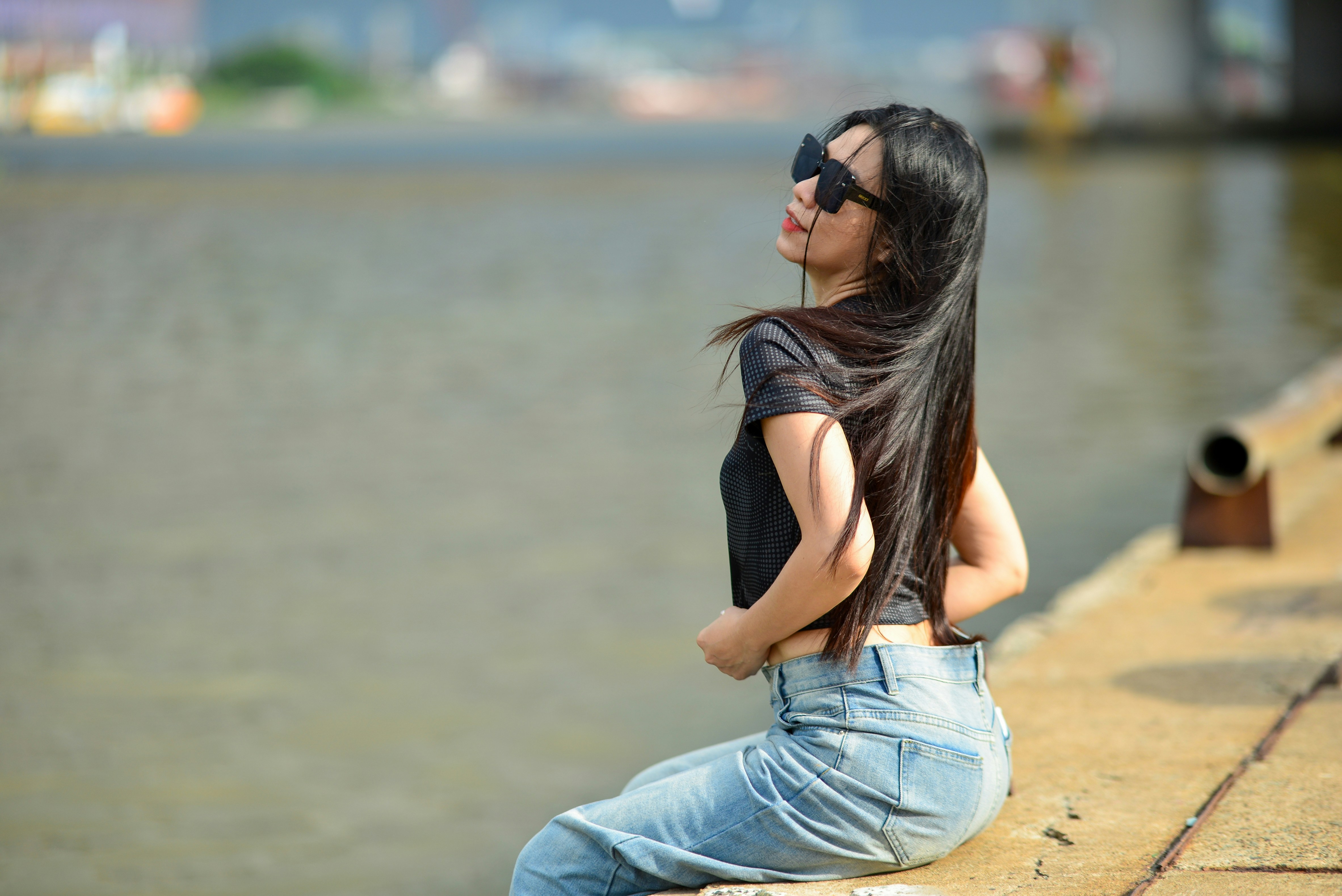 A woman with long dark hair wearing sunglasses and a black top sitting outdoors