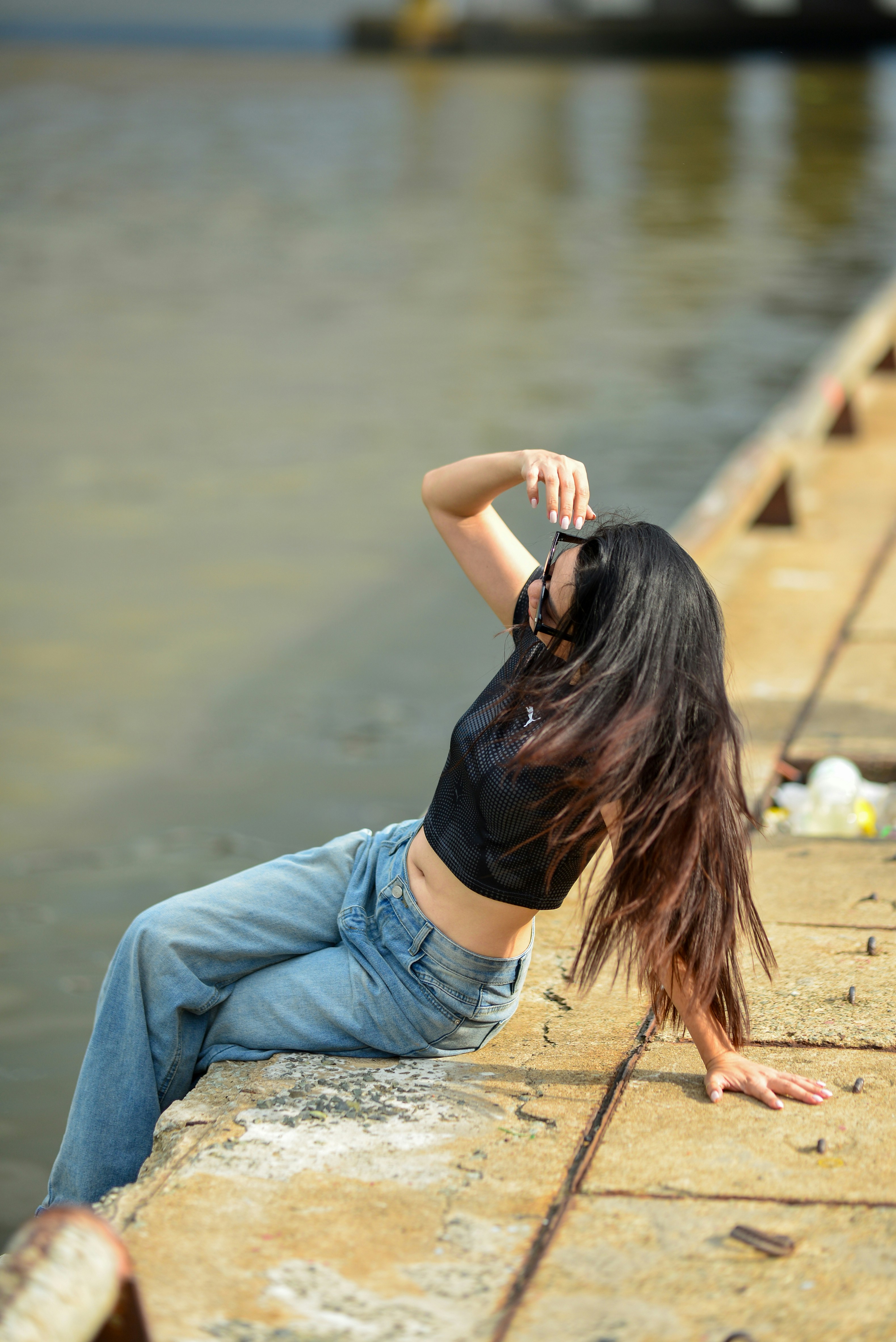 A woman with long dark hair wearing a black mesh top and jeans
